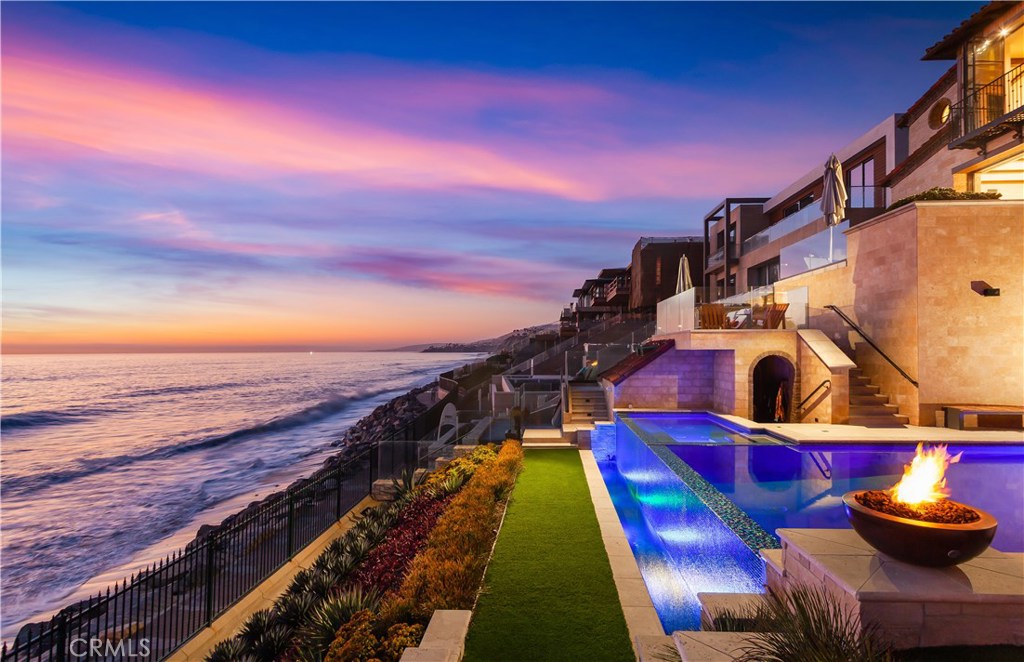 Crowning the very upper echelon of Southern California’s finest oceanfront homes, this custom tri-level masterpiece offers an extremely rare opportunity to experience life as few others can. Located on the front row of The Strand at Headlands in Dana Point, the modern Mediterranean showplace reveals breathtaking whitewater ocean views that encompass shoreline vistas, Catalina Island, dazzling sunsets and Headlands and Headlands Cove vistas. Views are enjoyed from nearly every location within the estate, which unveils Old World craftsmanship that complements today’s state-of-the-art and on-trend technology and appointments. Fold-away and hideaway walls of glass erase the border between indoor and outdoor living spaces throughout the home, and wrought-iron Juliet balconies, private patios and an entry courtyard beckon residents and guests outside. Approx. 8,823 s.f., the recently upgraded residence was built in 2018 and hosts 6 ensuite bedrooms including a separate guest villa and bunk room, 7 full and 2 half baths, a 5-car garage, 10-seat theater, and an Architectural Digest-worthy kitchen with hidden butler kitchen behind. The main-level great room opens to a view deck and shares a 2-sided fireplace with an office/library. Take the elevator to the lower level and discover an entertainment room with wine walls and a pub-style wet bar that flow to a resort backyard with infinity pool, spa, a built-in BBQ, varying seating levels, and access to the beach below