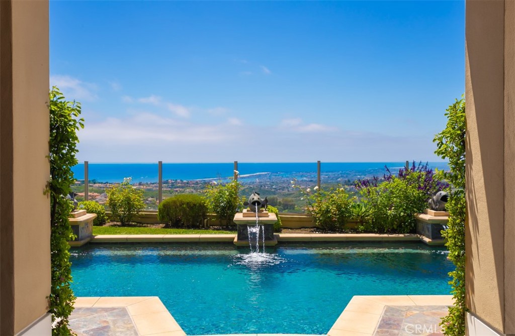 Championed on the best ocean view lot in guard gated Ocean Heights, 2 Via Rubino is perfectly positioned to capture unobstructed, 270 degree panoramic views of the ocean, coastline, city lights, and snow-covered mountains, creating a dreamlike backdrop from nearly every room in the house. Upon entry, one is greeted by a grand foyer that leads to an open concept floorplan, allowing for seamless transitions between the family room, kitchen, and living areas while showcasing exceptional indoor outdoor living. Having undergone an extensive multi million dollar renovation, this turn-key residence offers the highest quality finishes including Custom milled solid wood cabinetry, Cristallo quartzite countertops, chef grade appliances, and a mixture of beautiful stone and wood flooring throughout. Large, picture windows in every room highlight the dramatic views and allow an abundance of natural light to flood through every corner of the living spaces, creating a bright & airy feel to the entire home. The well designed floorplan provides spacious retreats for guests and residents alike, with a main floor guest suite, four en-suite bedrooms on the second level, two offices, and a spacious bonus room. The oversized primary suite has been expanded from the original builder footprint and includes designer finishes, custom built-ins, and breathtaking panoramic ocean, city lights, and snow covered mountains visible as far as the eye can see. This trophy property is completed with a resort style, wraparound backyard with pool, spa, outdoor BBQ area, and multiple covered and open-air sitting areas to take in the exquisite views. Available for the first time in over a decade, 2  Via Rubino is an irreplaceable property that exemplifies the pinnacle of Chic, coastal living and the best that Newport Coast has to offer.