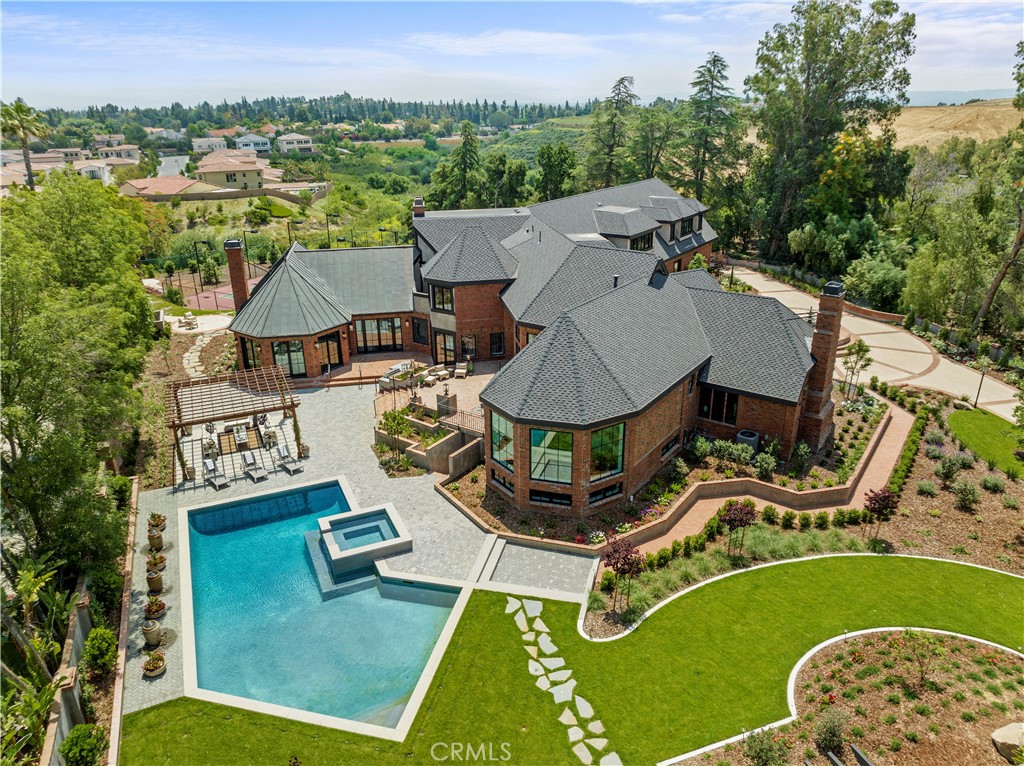 This luxurious, grandiose, and authoritative one-of-a-kind modernized Tudor estate home is exclusive, emanating opulence, exclusivity, and originality at every turn. Prepare to be dazzled by exceptional details and awe-inspiring craftsmanship that meld traditional and modern elements. Indulge in unparalleled luxury with over 10,000 sq ft of sumptuous living space, featuring a splendid living room with a wet bar perfect for entertaining, elegantly coved ceiling dining room, and an impressive hexagonal morning room that exudes grandeur. Savor the newly-renovated kitchen, showcasing a spacious waterfall center island, walk-in and butler's pantries. The family room is grand and Illuminated by walls of French doors framing scenic mountain vistas, a fireplace and breathtaking architectural detail and vaulted trussed ceiling. Experience the convenience of a well-appointed home office/library with custom woodwork, high trussed ceilings, arched doorways and a cozy fireplace. Upstairs, step into the extravagant primary suite with cathedral ceilings, a private balcony, retreat room and fireplace, a lavish bath boasting double sink vanities, and a third complete vanity area for makeup and hair, double walk-in closets and a luxurious soaking tub awaiting tranquility. The hallway will lead you to the elevator, a study station, laundry room and three guest en-suites and two additional guest ensuite available on the main level. The lower level includes a cedar wine cellar and tasting room, gymnasium, full bath, and dry sauna room. This remarkable property offers over two acres of seclusion and privacy, with orange groves, lush grounds, remarkable mountain views, a four-car garage, wood-paneled elevator, and horse-zoned wilderness. Indulge in leisure with the pool/guest house, tennis court, newly-built resort-style pool, spa, and terrace.The 24-hour guard gated community of Monteria Estates ensures privacy, security while being only minutes from fine dining, entertainment, shopping, world-class private schools and easy freeway access. You don't want to miss out on this incredible opportunity!