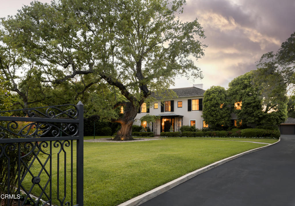Located within the highly coveted estates neighborhood of San Marino, this Regency Revival masterpiece was built in 1929 by the renowned architect Roland E. Coate. The home is set behind attractive iron gates and tall hedges at the front and is bordered by the Kewen Canyon at the back of the property to provide the ultimate in privacy. Attesting to its rich history and legacy, this was once the cherished USC Presidential Mansion. The home's luxury and elegance is highlighted by soaring ceilings, generously proportioned rooms, six fireplaces and an array of magnificent architectural details. Upon entering the home, one is welcomed into a long reception hall flanked by a large formal living room, the spacious dining room and a powder room. An enclosed loggia at the end of the reception hall features stenciled wood beams, an outfitted wet bar and arcade windows providing panoramic views of the meticulously manicured backyard gardens. A wood paneled library with fireplace is another gem of the house. The spacious gourmet kitchen, designed by Christopher Peacock, is decked out with a La Cornue range, a marble island with bar height seating, coffered ceiling and the highest quality custom cabinetry. A bedroom suite with a bathroom and adjoining office completes the main level. A grand staircase leads to the upper level presenting five bedrooms and four baths including a luxurious primary ensuite bedroom with fireplace and dressing rooms along with a junior ensuite bedroom with fireplace and dressing room. A large sun deck overlooks the backyard and beyond to canyon vistas. The basement, running nearly the length of the home, includes a wine cellar, storage rooms and a finished media room. Massive pocket doors, rolling window screens, operable shutters, and custom iron window grills showcase the era's masterful craftsmanship. The property has been renovated to a high standard exemplified by a walnut paneled elevator connecting all levels of the home. Immaculate gardens with oak, cedar, olive, magnolia and fruit trees grace this idyllic sanctuary. A lighted N/S pickleball/tennis flexible court, fountains, terraces, pavilions, glass mosaic tile spa and pool frame the backyard. Adjacent to the 3-car garage is a guest house with a bedroom, kitchen, bath and separate studio. Set in a prime location close to the Huntington Library, Lacy Park and the shops and restaurants along Lake Avenue, this property offers the utmost in privacy, comfort and modern sophistication.
