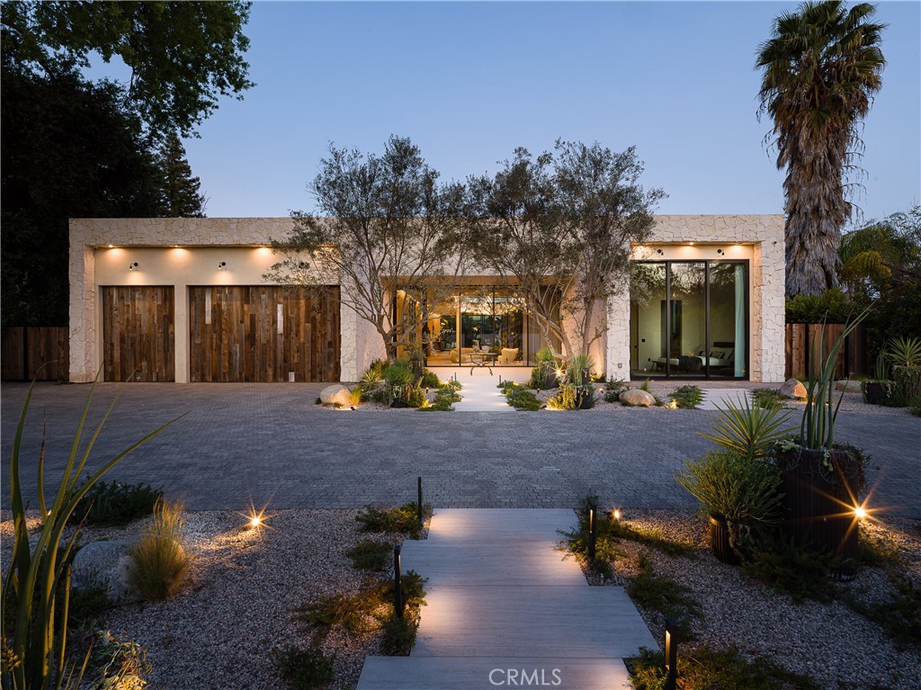 Unveiled as a triumph of architectural ingenuity, 5824 Manton Avenue is a beacon of organic modern design in Woodland Hills coveted Walnut Acres enclave—a masterpiece poised to grace Architectural Digest. Spanning 7,470 square feet on a single level, this gated estate features five bedrooms, six spa-inspired bathrooms, and a dedicated office, all on a 22,580-square-foot lot. Designed for visionaries, this gated sanctuary redefines luxury living with innovation and elegance. Inside, wellness and luxury merge in a layout built for serenity. Venetian Marmarino plaster walls shimmer with depth, while louvered plaster accents enhance curved fireplaces and a bar, adding sophistication. Organic materials, natural textures, and wood beam ceilings create a calming atmosphere, with 14-foot ceilings and an arched hallway elevating the ambiance. Floor-to-ceiling glass sliding doors blur indoor-outdoor boundaries, flooding the space with light and framing lush greenery. The heart of the home, an entertainer’s dream, centers on a gourmet kitchen with dual islands clad in custom oak cabinetry, arched alcoves, and fluted accents, seamlessly flowing outdoors through glass walls. A butler’s kitchen with a spacious pantry ensures effortless hosting. The living area, anchored by a curved fluted wall and travertine fireplace, creates a cinematic setting. A state-of-the-art movie theater and two atriums elevate the home’s offerings. The primary suite is a sanctuary, featuring two water closets, integrated travertine sinks, and a spa-inspired bathroom with floor-to-ceiling glass framing verdant views. A large walk-in closet with custom white oak cabinetry adds luxury and organization. Each bedroom reflects meticulous attention to detail. Outside, a curated front courtyard with mature olive trees and soft lighting sets a five-star tone. The backyard rivals exclusive resorts, with a 65-foot resort-style pool featuring floating stone water features, two sleek cabanas, and a private pickleball court. Lush landscaping creates a tranquil oasis under the California sun. Home includes energy efficient solar panels, Control4 smart home system manages lighting, temperature, cameras, and music. Located near the Los Angeles Rams’ training facility, and Westfield Topanga Mall. This sanctuary offers seclusion and accessibility. More than a home, 5824 Manton Avenue is a statement—a legacy setting a new standard for luxury living, where every detail tells a story of innovation and beauty.