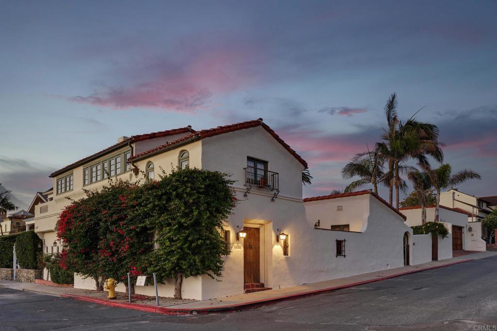 Lovingly named “La Estrella del Mar” in 1925 by Master Architect, Herbert Palmer, 306 Sea Lane is truly a treasure to behold! Situated on a coveted corner lot in La Jolla’s historic Beach Barber Tract neighborhood, just steps from the sand, this landmark Spanish home was meticulously restored in its entirety in 2005 by its current owners along with Trip Bennett, AIA and Grunow Construction, who carefully preserved and honored the home’s historicity while providing modernizations for everyday living. Elegance welcomes you as soon you enter the home and discover the arched passageways, solid walnut plank floors, beamed ceilings, plaster walls, antique Puebla tiles, and original woodwork that follow you throughout. Herbert Palmer’s signature blend of indoor and outdoor living can be found throughout this beloved home with access from nearly every room to a courtyard, patio, balcony, or private outdoor space. Perfectly designed for entertaining, the main level enjoys a formal living room with wet bar and fireplace at the front of the home, an adjacent dining room with antique brick ceilings and access to the 950-bottle wine cellar, an informal living room at the back of the home with vaulted ceilings and bi-folding collapsible doors that open to the outdoor dining patio and backyard, and the pristine chef’s kitchen that is located in the heart of the home with a large center marble island and access to the interior courtyard through custom iron French doors beneath original carved beams. Make your way up the original, hand-carved spiral staircase in the formal living room to the immaculate primary suite with ocean views through the bank of west-facing windows, a fireplace, walk-in closet, and spa-like bathroom with a Beaumanière limestone walk-in, steam shower and a separate Kallista clawfoot bathtub. Two additional generously-sized bedrooms can be found upstairs with a shared hallway bathroom as well as a private ocean view deck with a cozy, built-in sectional and outdoor speakers, providing an idyllic setting to watch the sunset. The fully-walled property is believed to be the only property in all of San Diego County that is built directly to the lot line on all 4 corners, utilizing all square footage and providing for spacious courtyard and backyard spaces. The private backyard features a large grassy area with surrounding gardens, an arched outdoor shower with Talavera tiles and an arbor with flowering yellow trumpet vines, a picturesque outdoor living space atop an elevated terrace with hanging star pendant lights and access to the detached two-car garage, as well as a fully-plumbed masonry outbuilding, which is believed to be the former staff quarters, that has been transformed into an art studio and gardening workshop. There are countless unique and historic details to take in as you make your way through this cherished home, as if each room has its own story to tell of its rich, nearly-100-year history with only a handful of owners. 306 Sea Lane is an exceptionally special property that presents a rare opportunity to own a piece of La Jolla history and to continue writing its story with new memories for years to come.