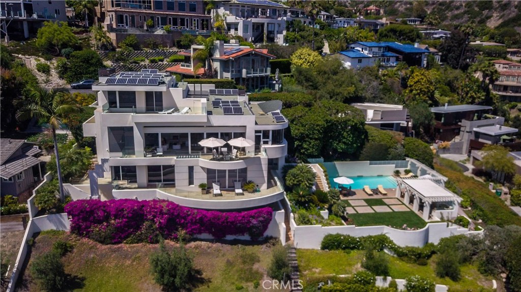 Iconic contemporary Family Compound or Corporate Retreat. Nestled in the hillside just above the Village, this impressive contemporary estate seems to float above the Pacific, with panoramic vistas of the ocean, whitewater, Catalina, sunsets, Main Beach and lights from nearly every room. This exceptionally private and secure property at the end of a quiet lane — within walking distance to town and the beach — spans nearly a half-acre with a 5 bedroom, 7 bath, approximately 6,700 sf residence. Here, spacious rooms feature walls of glass that open effortlessly to expansive wrap-around terraces, creating the ultimate setting for casually elegant living and entertaining. Highlights include solar power, elevator, two master suites, both with private terraces, a chef’s kitchen by Siematic with dual sets of appliances by Gaggenau, Miele and Sub-Zero, full gym with jacuzzi and sauna, state-of-the-art theater from Audio By Design that includes BluRay, AVD and Kaleidoscope Systems with 150 films, and a 1,500-bottle wine cellar. The secluded ocean view grounds live like a resort, with a pool, waterfall, green lawns, covered pavilion with full outdoor kitchen, vegetable garden, fruit orchard and dog run. (SEE VIDEO) Once in a lifetime opportunity! Build a guest house or split the lot and build second home. (with design review approval)