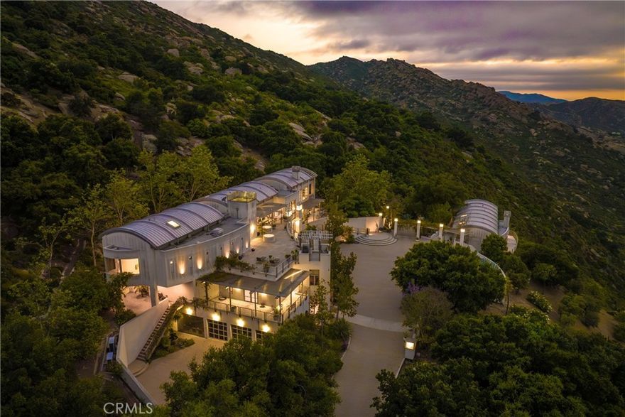 *** PRICE IMPROVEMENT *** Experience the awe-inspiring allure of this property located in the Santa Susana Knolls, boasting a captivating architectural masterpiece. Designed by the renowned David C. Martin, AIA of A.C. Martin Partners, this residential sculpture stands as a testament to power & drama. Nestled within an expansive landscape encompassing approximately 111+/- acres, this property is a feast for the senses. Enchanted by the iconic natural surroundings, featuring a striking display of rare plantings, majestic rock formations & waterfalls. With its undeniable beauty, this radiant residence transcends traditional expectations & leaves a lasting impression. The structure itself spans over 10,000 square feet, showcasing a harmonious blend of steel and glass. Indulge in the luxury of space with 5 bedrooms, 9 bathrooms, including an opulent master suite, library with floor to ceiling shelves, office, gym, media/bonus room, elevator & impressive wine cellar. The chef's kitchen boasts not just one, but two expansive islands, perfect for culinary enthusiasts with commercial appliances. Sunlight bathes the public rooms, creating an atmosphere of warmth & serenity. Step outside onto the expansive stone terraces & marvel at the breathtaking views of mountains & valleys that stretch as far as the eye can see. Additional features of this extraordinary estate include a self-contained guesthouse with two bedrooms, an infinity edge swimming pool & tranquil meditation gardens. Immerse yourself in the modern luxury that this property offers, all within a magical setting that feels worlds away, yet conveniently located just 30 minutes from the Westside & minutes from Porter Ranch. This offering is truly a rare & remarkable opportunity.