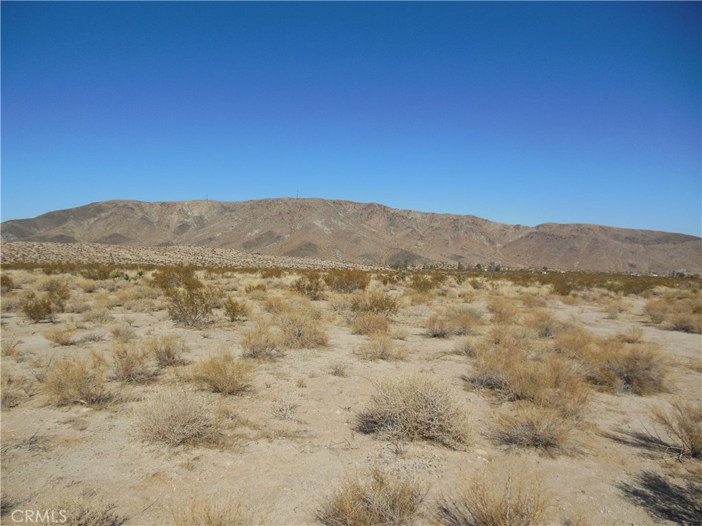 Discover an extraordinary opportunity with this remarkable 4.64-acre lot in Joshua Tree, boasting an impressive 330 feet of frontage along the iconic 29 Palms Highway. This rectangular parcel, measuring approximately 330 by 613 feet, is strategically positioned on the northern side of 29 Palms Highway at the intersection with Lee Road.
As the first parcel encountered when entering Joshua Tree from the east, or the last when traveling west, it serves as a prime gateway to this enchanting area. Lee Road acts as the boundary between Joshua Tree and 29 Palms, enhancing its accessibility. Conveniently situated midway between the western and eastern entrances to Joshua Tree National Park, this lot offers unparalleled potential.
With unobstructed vistas of the majestic mountains of Joshua Tree National Park to the south—including Queen Mountain, Quail Peak, and Eureka Peak—as well as Copper Mountain to the north, the possibilities for development are limited only by your imagination. Power lines run along 29 Palms Highway, and water services may also be available in the vicinity. This parcel falls within the jurisdiction of the Joshua Basin Water District, ensuring essential utilities are within reach.
**Street number has not been assigned. Numbercial reference is part of the APN**