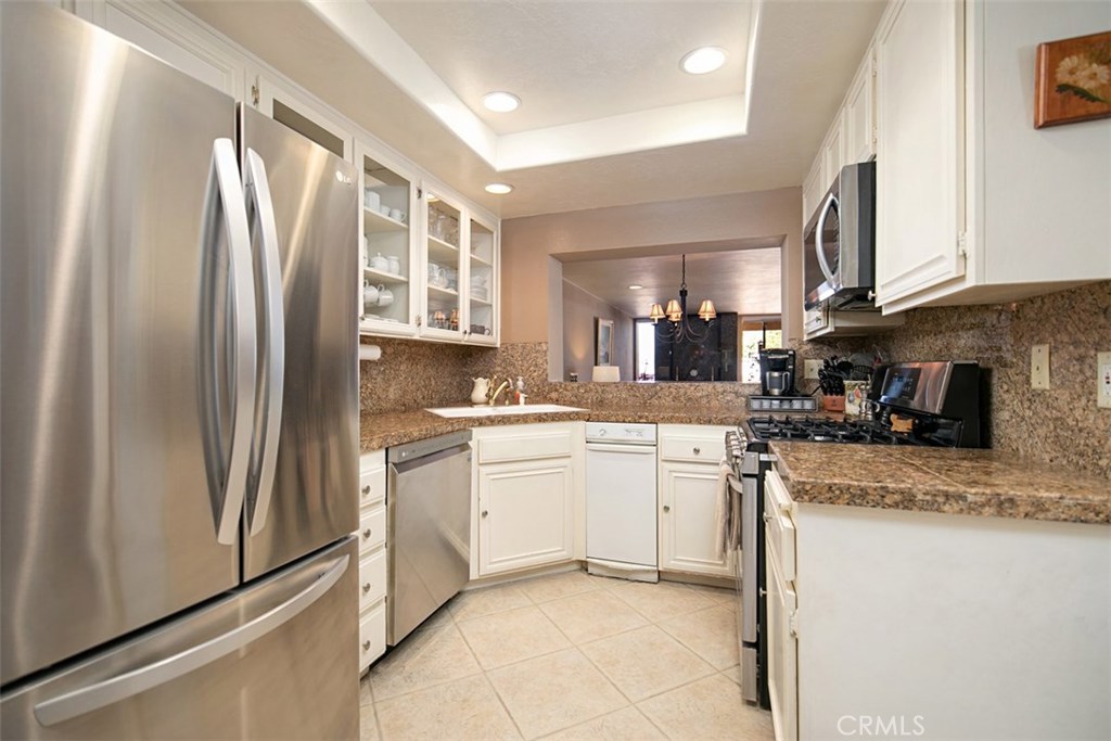 A must see! Resort style living... Lovely lower level condo with an open floor plan and lots of natural lot streaming through the home. Beautiful amenities with elegant flooring, recessed lighting, and smooth ceilings enhance the ambience. The kitchen offers a nook for eating, stainless steel appliances, and sleek granite counters, white cabinetry with glass inserts, plus travertine flooring. The gas fireplace in the living room is faced with wonderful granite tiles. A spacious patio can be accessed from the living room and the master bedroom, and in the evening relax and enjoy the view of the city lights. Newer carpet in the master bedroom, and a walk-in closet. In the master bathroom a large walk-in shower. Inside laundry, and a one car garage completes your marvelous home. A carport is assigned to the condo for a second vehicle. The Association offers a pool, and picnic area and the Association Dues cover water and trash. The condo is located close to the pool area, and close to Mission Viejo Lake. Mission Viejo Lake offers boat rentals for sailboats, kayaks, paddleboards, row boats, and pedal boats. Plus, many special events such as Movie Night, concerts and more. Enjoy the lifestyle of Mission Viejo Lake!