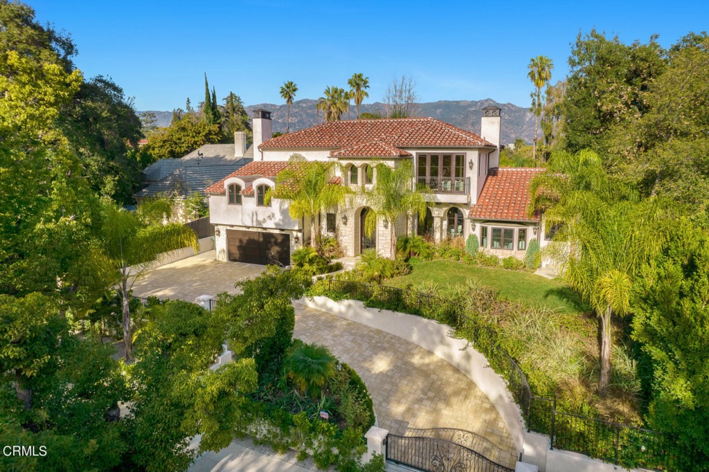 Located in the premier Oak Knoll neighborhood, a short stroll to the Langham Hotel and perched above the street, this gated modern Mediterranean home with pool and cabana offers the highest quality in custom finishes, details, and construction as well as impressive views of the San Gabriel mountains. Completed in 2019, the majority of the main residence as well as the entire cabana were built from the ground up with the remaining completely remodeled. An imposing custom wrought-iron front door invites you into the main floor living area and expansive gourmet kitchen featuring Viking and Bosch appliances and two islands. In addition there are two ensuite bedrooms downstairs (including a downstairs primary) and three ensuite bedrooms upstairs accessed by a dramatic wrought iron staircase featuring a gold-colored dome ceiling. The upstairs primary suite features hand-hewn truss beams, a stone wall with Montigo fireplace, a dramatic bath featuring a wall of Oceanside glass tile, a stand-alone soaking tub and an oversized dual-headed shower and custom walk-in closet. Perfect for entertaining, three sets of French doors open onto an expansive Versailles-pattern stone patio with salt-water pool, column-lined covered dining area, built-in barbecue and glass fire pit. The versatile cabana offers an open floor plan with hand-hewn truss beams, a kitchenette, bathroom with shower, and its own split-air unit. This exquisitely-finished custom home in a prime Pasadena location provides a refreshing modern take on Mediterranean architecture.