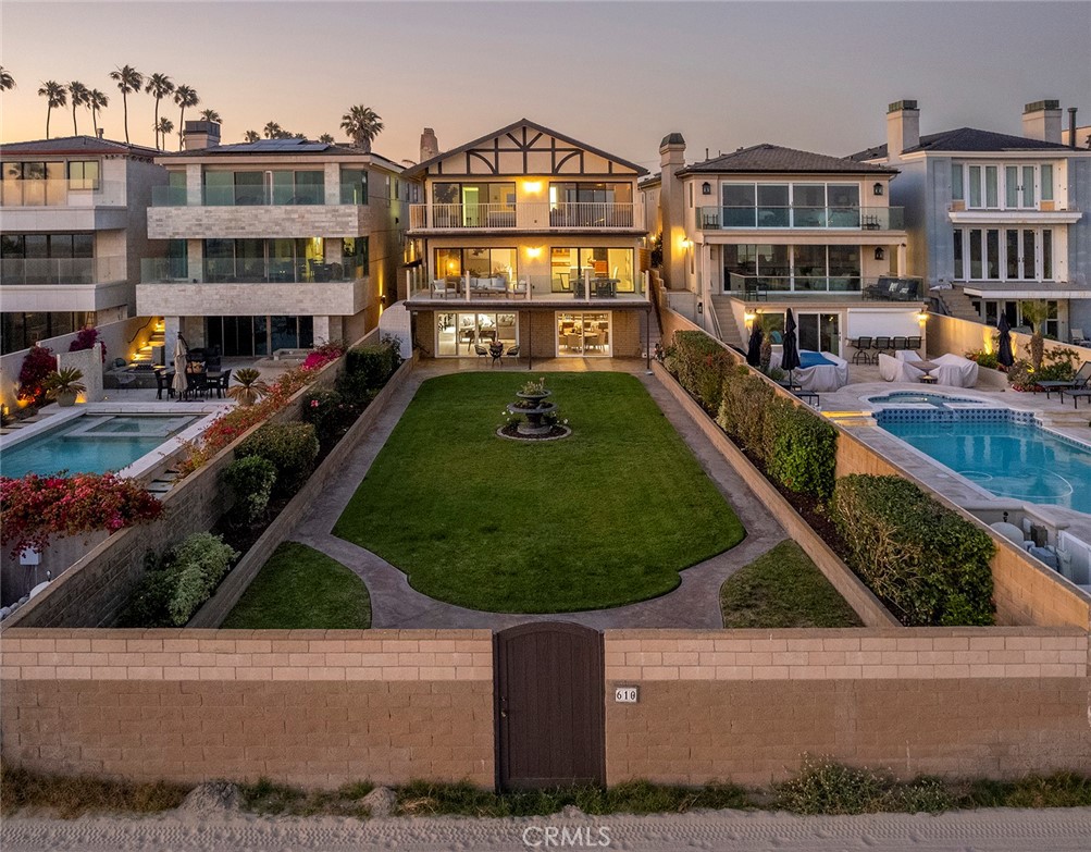 One of only 44 legacy properties situated along the famed “Gold Coast” of Seal Beach, these sought-after residences with north-westerly orientations beyond one of Southern California’s most historic piers, are rarely traded and remain within families for generations. This extraordinary offering is amongst a distinct collection of residential properties presenting a unique combination of square footage, waterfront elevation, and private gates that open directly onto the sand. The parcel of over 7,800 square feet with a verdant expanse of hedge-walled beachfront garden, and an uncommon 40’ of ocean frontage offers the ideal environment to surround the over 4,400 square feet of living space. An accommodating three-level home encompassing four bedrooms; five baths; myriad, generous areas for dining, relaxing, recreation, and entertaining – including a formal bar and two kitchens – enjoys broad and brilliant seaside views and a particularly thoughtful layout. The exterior environs comprised of two structure-width terraces accessed through floor-to-ceiling glass doors, along with a cloistered expanse of lush lawn extending onto one of the region’s widest soft-sand beaches, experience some of the most spectacular sunsets and outstretched ocean vistas. Further distinguishing this exceptional respite is optimal proximity to Orange County’s finest amenities and the lifestyle afforded by this charming idyllic community.