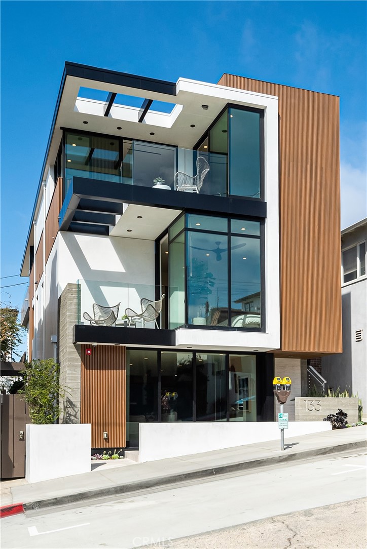 Renowned South Bay builder Kim Komick had two things in mind when designing her own dream home by the beach: keep the design simple and stunning using sturdy, natural materials; and create a welcoming environment for family and friends. This three-bedroom, three-and-a-half bath custom home, built in 2022 and encompassing 3215 square feet on a 2099 square foot lot, is the culmination of her life’s work, resulting in a California Contemporary with jaw-dropping views just steps from her beloved Pacific Ocean. Three levels rise to the sky with warm wood, glass, steel and concrete and house a luxurious abode with gorgeous details in an open, airy floorplan. The topmost level boasts a state-of-the-art kitchen, customized with sleek Neolith porcelain countertops and a Fisher & Paykel professional-grade appliance package, complete with dual drawer dishwasher, a six-burner professional gas range, a 30” refrigerator tower and an 18” freezer tower. A built-in coffee maker, warming drawer, conventional oven and vacuum seal drawer are also included, as are a full-size, 2-zone wine cooler and beverage fridge. The kitchen’s European-style walnut cabinets add warmth and dimension to this spectacular space. The light-filled living room is complete with corner sliding doors that fold away to create a true indoor/outdoor haven onto the ocean-view deck, while a concealed projector descends from the ceiling. On the opposite end of the kitchen, a sunny office space and eye-catching powder room provide the ideal spot for working, with the sun, surf, and sand offering the quintessential Southern California backdrop. The second level is home to a well-appointed Primary suite, a space to relax and unwind with panoramic views of the ocean from the private deck. A unique EMF-neutral (electromagnetic frequencies) environment ensures a restful night’s sleep. The extravagant bath beckons with a walnut dual vanity, soaking tub, and Serene-steam integrated system shower. A second bedroom suite with private entrance and kitchenette are also found on this floor, providing the opportunity for a unique flex space. A laundry room adds convenience to this floor as well. The ground floor features a vast beach room with Murphy bed, indoor/outdoor bath with beach shower, and an additional wet bar. A three-stop elevator, two-car garage, white oak floors throughout, full security system (including four cameras), and central surround-sound are just a few of the comforts found throughout the home.