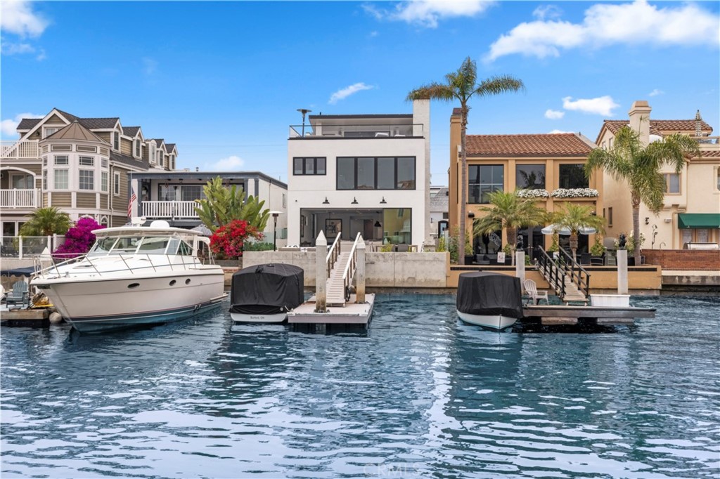 Offering the truly rare opportunity to enjoy the rewards of a brand-new home directly on the water in Newport Beach, this stunning transitional showplace offers spectacular bayfront views and a warm, bright and open living environment. An effortless balance of indoor and outdoor living spaces maximizes enjoyment and views from the residence, which reveals four ensuite bedrooms and five baths in approximately 3,166 square feet. The main level is ideal for impressive entertaining and daily relaxation thanks to an open-concept design that blends a living room with fireplace and surround sound, a dining room and a fully appointed kitchen into one seamless space, all opening via slide-away glass doors to a grand patio with a private dock. Only the finest appointments are featured in the kitchen, including white Shaker cabinetry, an island with bar seating, a pantry, open shelving, a full-sized wine refrigerator and top-tier stainless steel appliances. An elevator serves all levels of the home, including a top-floor bonus room that opens to a private view patio with a fireplace and outdoor kitchen. The oversized primary suite is a luxurious oasis complemented by mesmerizing bay and city-light views, a fireplace, large rain shower, a stand-alone tub and dual sinks. White oak plank flooring, shiplap, designer tile, contemporary lighting fixtures and high ceilings are showcased throughout the home, which boasts a design by renowned architect William Belden Guidero. While seemingly away in a waterfront world of its own, the custom masterpiece is merely moments from miles of beaches, Channel Park, Balboa Island, Fashion Island, high-end resorts and Newport Beach’s outstanding schools.