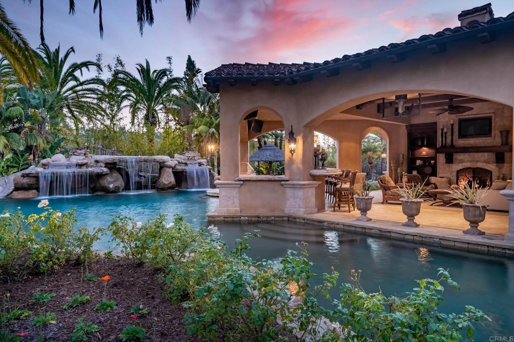 Awe-inspiring gated compound spanning over two acres in a secluded setting. Be transported to a European oasis with the estate’s impeccably manicured grounds and stunning architecture. An entertainer’s paradise, the home features a game room, lavish home theater, walk-in wine cellar, fitness studio with refreshment bar, putting green, fire pit, phenomenal pool with waterfalls, grotto spa and bridge, outdoor living room with fireplace, resort-like yard, and much more. The entry courtyard greets you with relaxing water features and a dramatic entry that leads to the smart single level floorplan with generous en-suite bedrooms, handsome executive office, children’s bonus room, and a detached guest house. The sumptuous primary suite enjoys a spa-like bath with steam shower, wet bar, and outdoor courtyard with fireplace and jacuzzi, providing comfort, luxury, and privacy. Gourmet kitchen with extensive cabinetry, center island, top-of-the-line appliances, dining nook and glass doors opening to the yard. A spacious 6-car garage and motor court provide ample parking space. You will feel as if you are always on vacation while living moments from local shops, restaurants, and entertainment.