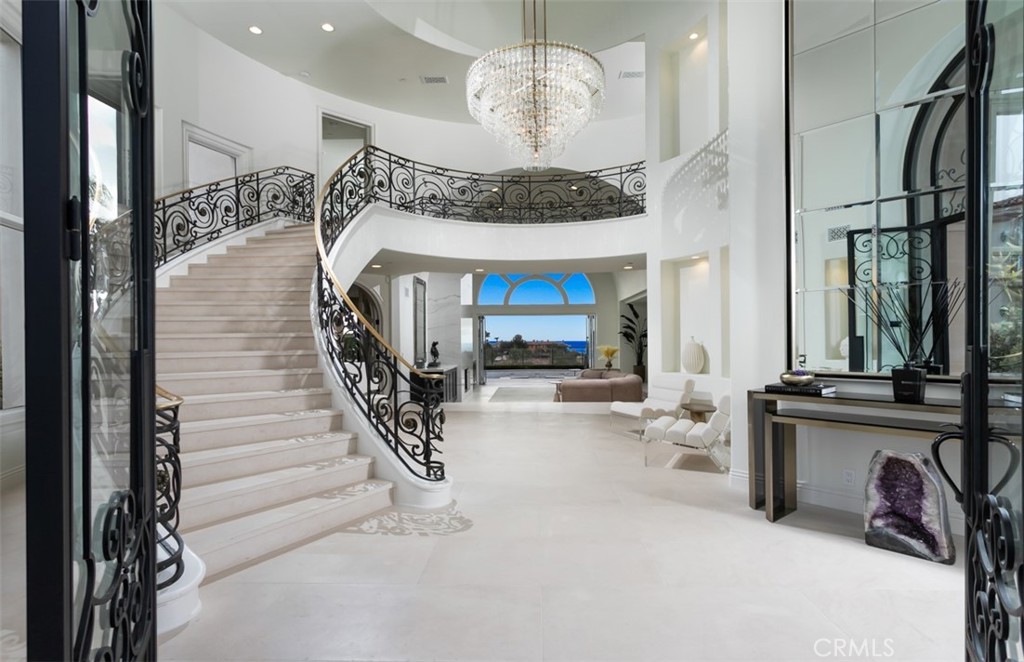 Nestled behind the exclusive gates of Pelican Ridge Estates, 17 Telescope boasts a private lot with dramatic ocean and coastline views. The newly renovated custom estate has been adorned with designer finishes and boasts a near stud down renovation with bespoke transitional finishes. The ~5,916 sqft. 5 bed + 6 bath home invites residents and guests alike with a grand interior with an impressive two-story foyer, spiral floating staircase, and catwalk which accentuate the breathtaking coastline views. The turnkey residence offers exceptional finishes such as glass and iron front door, pre-cast clad exterior, French limestone and French oak floors, slab stone kitchen waterfall island & backsplash, gourmet chef's kitchen with Meile appliances, 8 car “dream” garage wrapped in custom Cleaf cabinetry including commercial grade refrigerator/freezer, custom ventilation & designer lighting throughout, and whole house automation. The true open concept floor-plan is complimented by an open and bright living space on the first floor, made possible by 20 foot soaring ceilings which deliver a sense of occasion; the remainder of the home provides seamless transitions between the living room, family room, gourmet kitchen, and outdoor entertainer’s dream backyard complete with resort style pool and sit down coastline and city light views. The main-floor bedroom provides an ideal retreat for guests, while 4 ensuite bedrooms upstairs, including a luxuriously appointed master suite with exceptional panoramic ocean views, highlight the upper level. The custom estate is rounded out by a rare 2,400 sq. foot 8 car “dream garage” along with immediate proximity to Pelican Hill Resort and their championship golf courses, Crystal Cove Beaches, Orange County’s premier shopping, award winning schools, and resort-style beaches.