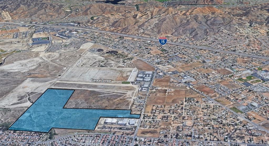 The subject property is located in Lake Elsinore, California and consists of a total of 132.24 Acres. The property is relatively flat in topography to which the majority lies underneath both the 100 and 500 year flood plains. The property is situated just West of Interstate 15 near the north-west corner of Corydon Rd and Plessner Way. This location is less than two miles from I-15 at Bundy Canyon and 2 ½ miles from I-15 via Diamond Drive. On the east end of the property is an existing 16,800 SF industrial building for which the only current access provided to the structure is by means of dirt roads. The structure has both roll up and sliding doors on the north side of the building and is ideal for airplane storage. The property then extends northwest along several industrial buildings before opening up and bordering a medium density residential community on the south side of the property and Lake Elsinore Airport on the north side of the property. Immediately across Corydon Rd are several small, occupied manufactured homes. The subject property has approximately 260 feet of frontage to Corydon Rd as the majority of the land is located on the west end of the property.