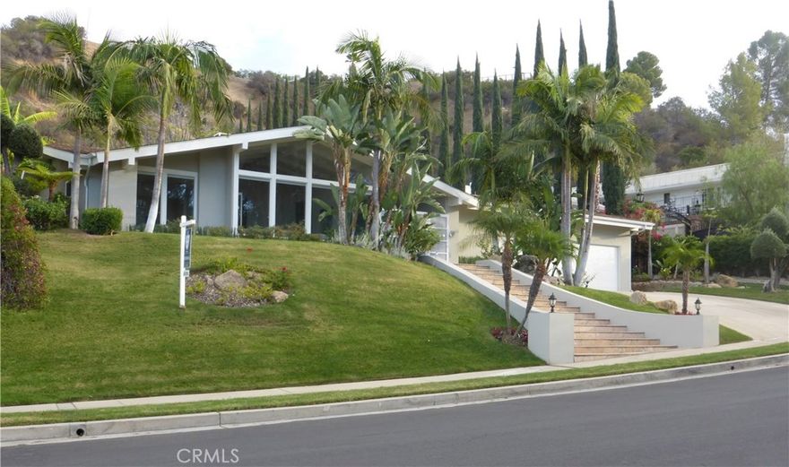 Majestically perched to accommodate mountain views during the day and valley lights at night! This stunning one story home is flooded with natural light and boasts 4533 s.f. of luxury living with 5/BR/4.5 BA. Chef's kitchen with Thermador appliances and granite counter tops. Very private entertainers backyard with grand flagstone patio, pool, fire pit.  A seamless flow from indoors and outdoors leads to a covered patio, rose garden and magnificent waterfall cascading down the hillside. Floor to ceiling windows, beamed vaulted ceilings, custom molding, two fireplaces with custom mantels.  A separate wing accommodates 4 bedrooms with en suite. An amazing Master bedroom with views of pool and gardens, two large custom walk in closets, sitting area, en suite in Carrara marble, with Kohler digital shower spa and contemporary stand alone tub.  The 5th bedroom with bathroom is ideal as a guest/nanny/maid's quarters.  A 6th room with built-ins is perfect as an office, den, or media room.   A sense of warmth and comfort permeates the entire home as if you are vacationing in a private resort away from it all.   Three car garage, separate laundry room and lots of storage.  Beautiful home set on a spectacular 26,950 sf lot!