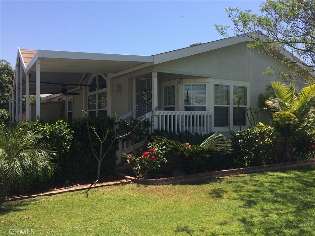 Beautiful mobile home that has been updated with new flooring, baseboards, new paint, doors, trim moldings, blinds, light fixtures, etc. Spacious, open concept with lots of light. Large kitchen with newer stainless appliances. Large covered patio on the side for entertaining. This unit is located in the middle of the quad surrounded by grassy areas. Many beautiful plants surround the property - Plumeria trees, Hibiscus plants, roses, etc. Storage shed is on the side of the property. Park rent is $1175 per month and there are 20 years left on the lease.