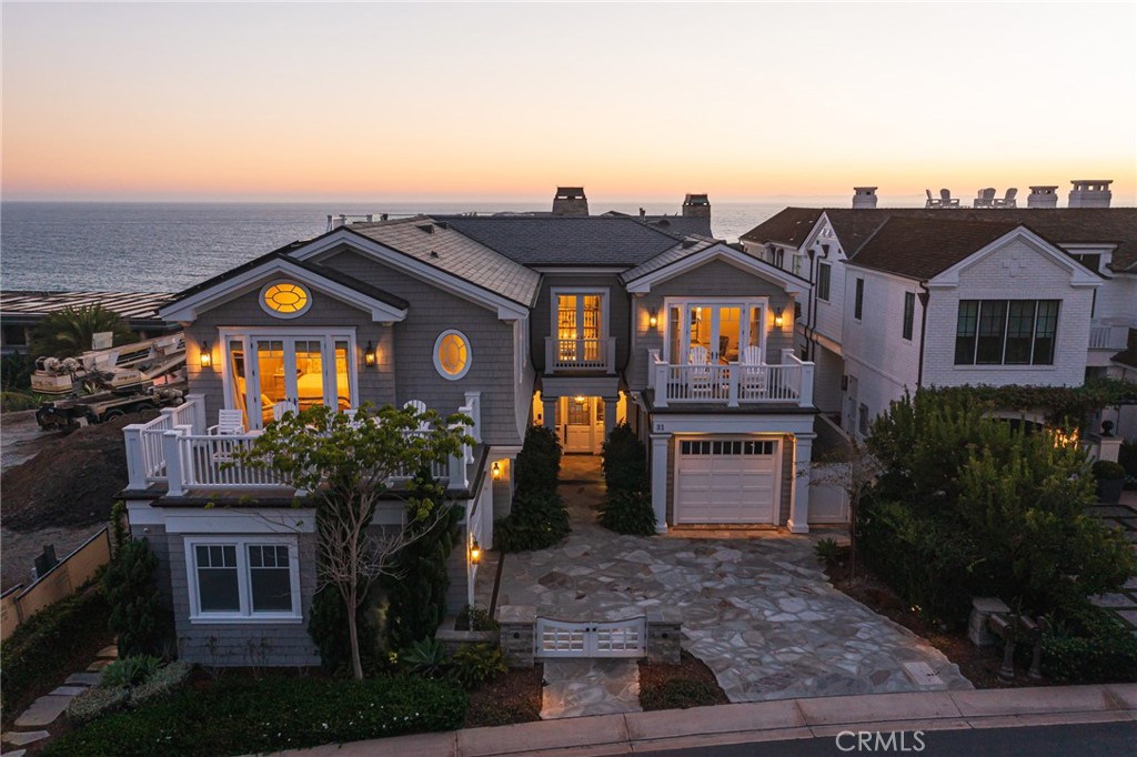 Endless ocean views dazzle from virtually every vantage point inside and outside at this luxurious Hamptons-caliber custom estate at The Strand at Headlands in Dana Point. From Dana Point’s imposing namesake bluff, across a white-sand beach and breaking waves, out to Catalina Island and colorful sunsets and up the coast as far as Palos Verdes, the home’s panoramic views are ever-changing by season and time of day. Meticulously crafted architecture showcases shingled New England charm on the exterior that complements a crisp, white interior with extensive custom millwork, large windows and handsome wood flooring. A double-height entry with leaded-glass door and a stunning staircase makes an appropriately grand first impression and leads the way to a three-level floorplan that spans approximately 6,659 square feet. Ocean views are enjoyed upon entry and continue in a home office, a formal dining room with large bay window, and a blended great room and kitchen area with fold-away glass doors to a dining patio, built-in BBQ bar, a pool and putting green. Walker Zanger marble countertops add an air of sophistication to the magazine-caliber kitchen, which is fittingly appointed with white cabinetry, an oversized island with farmhouse sink, a massive Wolf range with pot filler, a built-in refrigerator and Thermador and Miele appliances. Five ensuite bedrooms, five- and one-half baths, a movie theater with tiered ceiling, and a three-car garage are also showcased. Upstairs, the primary suite reveals breathtaking ocean and whitewater views, two fireplaces, a sitting room, two decks, a walk-in closet with custom built-ins, a stand-alone tub and a large rain shower. For the ultimate view experience, a spacious rooftop deck offers uninterrupted vistas in all directions. Located halfway between Los Angeles and San Diego, The Strand at Headlands is a private, gate-guarded oceanfront enclave of custom homes in the heart of the Orange County Riviera. Moments from the Ritz-Carlton, the Monarch Beach Resort and the Montage Resort & Spa, the 121-acre Strand collection includes more than one mile of coastline, with 70 acres of parks, open space and 3 miles of coastal trails. The Strand Beach Club is a private 9,000 s.f. clubhouse with fitness center, swimming pool, bar and open lounge. Noted as the last new-home enclave along Southern California's world-famous coast, The Strand is close to high-end shopping and dining, Dana Point Harbor and endless recreational destinations.