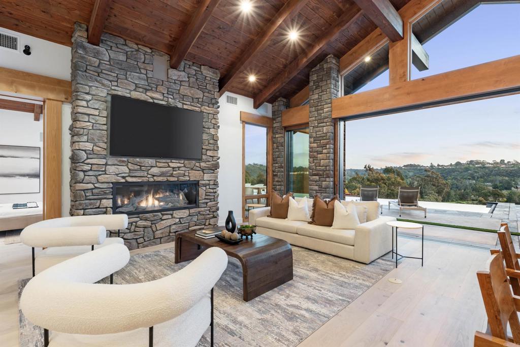 Perched atop the picturesque western bluff of Rancho Santa Fe, discover this impeccably crafted, modern oasis boasting unparalleled luxury and convenience. Just remodeled by luxury home builder Munsch Homes with meticulous precision and an emphasis on cutting-edge technology, this custom-built 4-bedroom residence offers seamless single-level living. Set upon a fenced nearly 3-acre lot, accessed by a secluded gated private driveway, the home captivates with breathtaking vistas stretching across the serene countryside in both northern and southern directions. Home includes: hand-cut stonework, Douglas Fir and Knotty Alder custom wood, 22' vaulted ceilings, double wall and door framing, Lowen windows, pivot doors, Rocky Mountain hardware, huge indoor-outdoor pocket doors, motorized outdoor shades, Du Chateau plank flooring, Subzero, Wolf and Miele appliances, Electric Mirrors, Gessi fixtures, a spa-like primary bathroom indulges with a glass-enclosed master shower, solar systems for residence/hot water & pool, professional grade security throughout, high-end RTI based audio/visual security, Xtreme 5' gas fireplace, whole house backup generator, double wall insulation, lots of discreet storage, plus much, much more. Outside, an infinity edge pool beckons, offering a serene oasis to relax and entertain against the backdrop of panoramic views. Multiple outdoor seating areas, including a custom gazebo. There is an orchard steps from the home with avocado, apple, pear, lemon, lime, orange and pomegranate trees. This is more than just a home; it's a sanctuary of modern luxury and comfort. The natural materials, and neutral palette used is so integrated with the surroundings that it inspires relaxation. Enjoy the added privilege of exclusive easement access to the neighboring 1000-acre San Elijo Lagoon Ecological Reserve trails system, ensuring a seamless blend of nature and sophistication for the discerning homeowner.