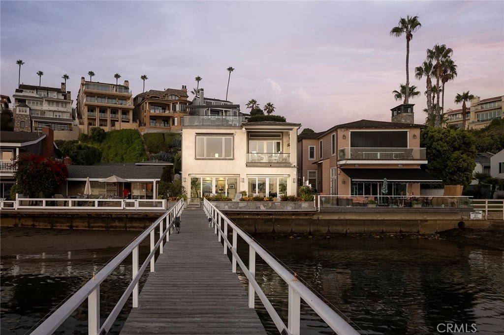 Designed in harmony with the bay, this premiere waterfront estate offers unrivaled views, scale, and amenities alike. The ornate living spaces are laid out over three floors and offer approximately 6,437 square feet of light-filled interiors characterized by picture-perfect views of the harbor, boats, and glistening city lights. The main level hosts three en suite bedrooms, a tranquil atrium with an above-ground spa, wine cellar, fully-equipped laundry room, and formal dining room. The centerpiece of the home is the great room featuring multiple sliding glass doors that frame the endless water vistas and lead to the shared pier with a private slip and side tie. A bespoke eat-in kitchen is outfitted in granite countertops, Viking appliances, and custom cabinetry surrounding a large center island. Ascending one level, appointments include a large office and an opulent master suite occupying a separate wing of the home and features a sitting room, balcony, sauna, steam shower, and walk-in closet. The third floor is dedicated to the game room that can be used as a fifth en suite bedroom and an exercise room which has direct access to the approximate 825 square foot entertainer’s deck where a fireplace, private barbecue, multiple al fresco dining areas, and panoramic views of the bay create the idyllic setting for large scale gatherings. Additional highlights of the home include heated tile flooring throughout and a convenient setting near Fashion Island shopping center, upscale dining, golf courses, and famous beaches. Curated to deliver the ultimate bay front lifestyle of superb comfort and convenience, this exquisite residence takes luxury living to new heights.