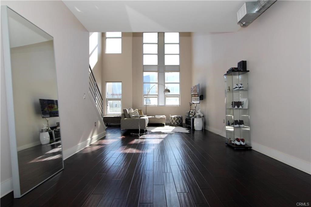 Ideal Location within the Santiago Lofts! Modern upgrades and fixtures are true highlights of this residence. Located adjacent to the Santa Ana Train Depot and just a few blocks from Downtown Santa Ana, an urban center for OC featuring emerging arts, restaurants, craft beer, cocktails and cutting edge culture. The Santiago Lofts are live/work lofts and widely acclaimed as the premier urban community, winner of the prestigious Urban Development Design Award. The modern design is carried throughout this expansive 1585 Sq.ft. Loft with wood floors, and two-story ceilings and windows. The home features a main floor commercial/retail workspace with an industrial-style rollup glass door. The main residence features open spaces and abundant natural light from the floor to ceiling windows. The gourmet kitchen includes white modern cabinetry, grey counter tops, and stainless appliances. The great room can be configured as a traditional family room, or open entertaining space. Bright and open loft space, which make for a perfect home office, or may be converted into a 2nd bedroom. The spa-like master bath includes a glass shower, with white subway tile accents, and newer marble floor tiles. Additional features of this home include a 2-car direct access garage with epoxy floors, and newer water heater, all within one of the most desirable floor plans within the community.