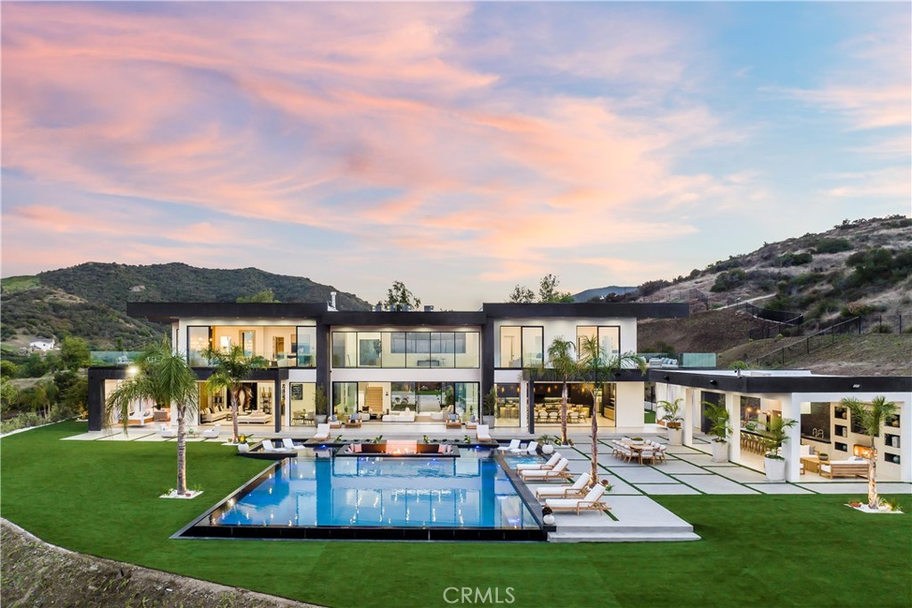 Experience the perfect blend of breathtaking panoramic views and serene privacy in this exquisite home, perched high in the sky over Malibu and nestled amongst the clouds - a true dream retreat. This stunning Malibu estate is a true masterpiece of architectural design and private, luxurious living. Nestled on approximately 50 acres in the hills of Malibu, this property offers the perfect blend of timeless character and modern amenities, all while providing breathtaking views of the surrounding landscape. As you arrive, a long and secluded private driveway leads you to an oversized motor court, where a trickling waterfall welcomes guests. Upon entering the home through double-height glass doors, you're greeted by an elegant foyer with soaring double-height ceilings.The grand salon, featuring a double-sided fireplace and floor-to-ceiling glass doors and windows, seamlessly connects the indoor and outdoor spaces, framing the picturesque views of the entertainer's backyard and the sweeping landscape beyond. The open-concept main level includes a living and dining room, family room, and massive pocket sliding glass doors, allowing for the quintessential indoor/outdoor living experience. The chef's kitchen is a culinary haven, equipped with top-of-the-line appliances, a large center island/breakfast bar, a butler's pantry, and a sun-drenched eat-in dining area with custom built-in features and a wine display. Upstairs, five en-suite bedrooms offer luxurious accommodations with views that are perfect for both family and guests. The primary suite, spanning approx 2,800 square feet, boasts a spa-like bathroom, a custom walk-in closet, and a private balcony overlooking the vast lot and stunning vistas.The outdoor area is an entertainer's dream, featuring an approximately 3,600 square foot infinity pool with a large spa, a baja shelf, and a sunken fire-pit. The backyard also includes a covered cabana and a full outdoor kitchen with bar seating. This self-sustaining property, situated on solid bedrock, offers endless possibilities, including the potential for large sports courts and even a personal vineyard. This estate offers a truly exceptional lifestyle and is conveniently located just about 7 minutes from Westlake Village and 12 minutes from the beach.