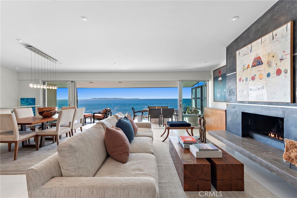 Breathtaking Pacific Ocean views, meticulously reimagined interiors, and exquisite outdoor living spaces unite in one incomparable Laguna Beach home that showcases the extraordinary design talents of architect Chris Light. An inviting entry opens to a private front patio that extends living areas to the outdoors and frames gorgeous ocean views through walls of glass. Indoors, the upgraded residence combines dramatic ocean vistas with natural wood finishes, a custom fireplace anchoring the living room, a wine wall, and access to a covered ocean-view deck. Fleetwood glass doors provide seamless transitions between indoor and outdoor living spaces, and a vaulted ceiling lends an overwhelming sense of spaciousness to the two-story design. Approximately 2,374 square feet, the home continues to impress with a Pacific-view dining area that flows directly to a top-tier chef’s kitchen with breakfast bar, frameless wood cabinetry and open shelving. A skylight illuminates the kitchen’s preferred stainless steel appliances, including a built-in Sub-Zero refrigerator, Bosch dishwasher and a six-burner Wolf cooktop. An elegant bath and walk-in closet elevate living in the primary suite, which is located on the main-level for easy single-level living. Step onto the balcony from the primary suite and take in panoramic ocean vistas and fresh sea breezes over morning coffee. Four bedrooms and three- and one-half baths are featured, with three bedrooms located on a lower level that is highlighted by a generous secondary living space that makes an outstanding media room and opens directly to an oversized backyard. Privacy and ocean views complement the backyard’s built-in BBQ, extra-large spa with waterfall, a fire-pit and after-beach shower. Entertaining loved ones and hosting them for extended stays is easy in this thoughtfully arranged open floorplan. Across the street from the steps down to Victoria Beach and it’s iconic Pirate Tower, this turnkey home is merely minutes from fine and casual dining, art galleries, the Montage resort, golf, and Laguna Beach’s enchanting village. Plan your private tour today and prepare to enjoy the ultimate ocean-view lifestyle.
