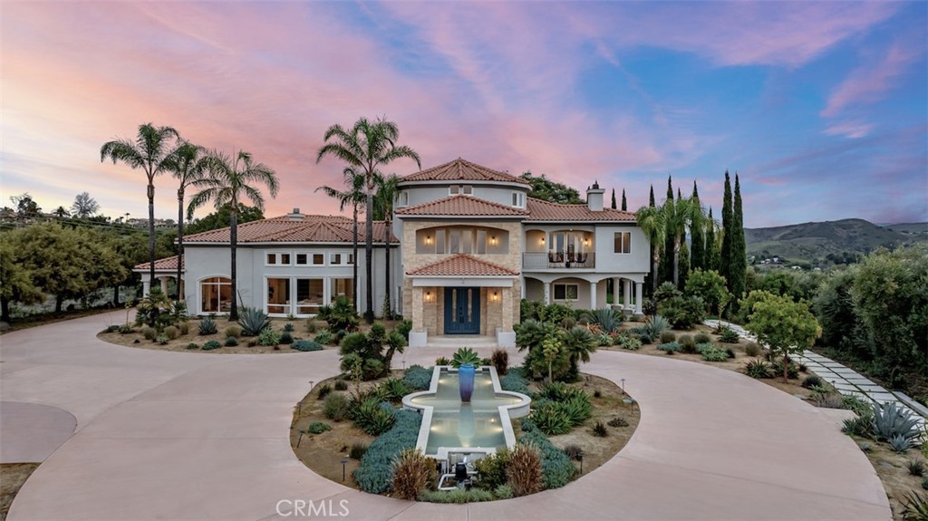 Welcome to a truly one-of-a-kind majestic property nestled on over 20 acres of breathtaking Santa Rosa Valley. Panoramic 360 degree views of the city, mountains and ocean create an epic picturesque setting. Located within the exclusive gated equestrian-estate community of Lexington Hills, this sprawling Mediterranean-style hilltop estate offers unparalleled privacy and prestige. Upon arrival, find a private long driveway, a roundabout and a 5-car garage. Immerse yourself in the grandeur of over 11,000 square feet of meticulously crafted spaces. With 8 bedrooms, 10 bathrooms, an office, game room and a home theatre, this is a masterpiece of design and luxury living. Step into the residence to be captivated by the grand ceiling heights, with a curved staircase leading to the second level. Natural materials, intricate molding and vast windows make every room a symphony of gorgeous lighting and details. The central courtyard takes center stage with french doors leading out from the kitchen, family room and formal living room. The bathrooms have been artfully redone with custom finishes. The updated kitchen boasts top-of-the-line Thermador appliances. The primary suite provides a sitting area, walk-in closet, and an expansive bathroom with a spa like shower and soaking tub. Outside, the property exudes a Tuscan-like setting with lush foliage. A spacious pool is complete with a waterslide, waterfall, swim-up bar, two spas and ample lounge areas. An acre-large flat area beckons an equestrian center or guest house. Some recent upgrades include water filtration, wifi tower installation and a generator. This estate is located in an award-winning school district, and only minutes from dining and shopping. This is a rare opportunity that merges luxury living and natural splendor.