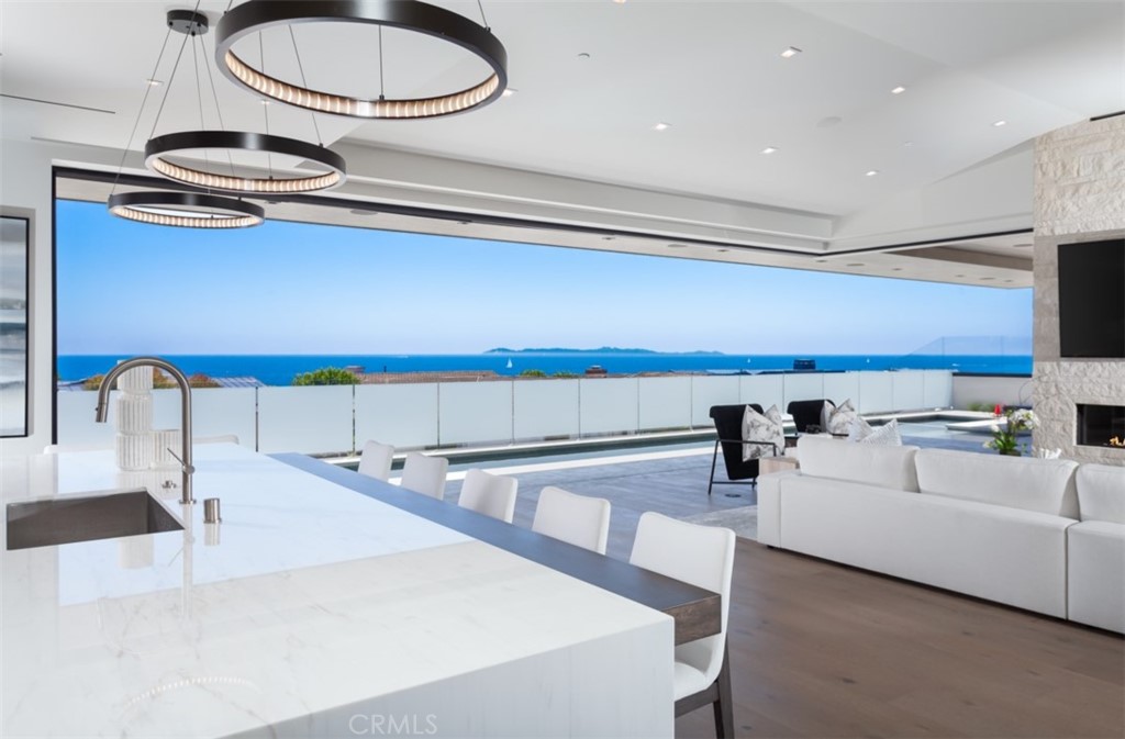 Located on one of the most premier view lots in all of Cameo Shores, 4527 Perham has been exceptionally designed by renowned architect Mark Teale and master crafted by SC Homes. The newly built ~9,100 sqft. 5 bed + 8 bath custom seaside residence has been curated for ideal functionality and positioned to optimize the panoramic ocean vistas. Through the custom iron gate and glass front entrance, to the pocketing wall of custom Fleetwood door systems, guests will enjoy breathtaking views of the Pacific Ocean, Catalina Island, and the Newport Beach Jetty. The level of design in the property and attention to detail is unparalleled and truly the work of artisans and specialists. The great room is designed to maximize sit-down ocean and jetty views while the 5 sets of pocketing doors seamlessly weave the indoor and outdoor spaces into one. The chef's kitchen provides professional grade Sub-Zero and Wolf appliances along with custom crafted cabinetry, imported Italian marble countertops. Supplementing the main kitchen is a secondary prep kitchen with a full size Sub-Zero refrigerator, Wolf 6 burner range, and direct access to outdoor spaces. Off of the great room & kitchen, the 35' cantilevered lap pool and spa showcase the architectural design and attention to detail put into the property. The main level is highlighted by a beautiful primary suite with exceptional coastline views and a dual vanity primary bathroom with two showroom style closets totaling 1,000+ sqft as well as a secondary laundry room. There are also four additional secondary suites as well as an elevator. A very rare feature is the walkout day-lit lower level which includes a screening/movie room with paneled walls and starlight ceiling, bar/lounge with beautiful custom cabinetry & designer lighting, game room, dedicated glass enclosed gym, a secondary bedroom suite and an approximately 2,500 sf automobile showroom garage with space for ~ 10 cars with viewing windows into the lounge and with a spacious outdoor covered living area & lawn. The property is completed with a savant smart home system. For any discerning buyer that has the very highest expectations for design, luxury, usability and functionality...your expectations will be exceeded on every level at 4527 Perham.
