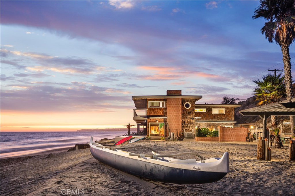 Beach Road is a guard gated coastal enclave with nearly a century of tradition and allure as an idyllic location for ocean-oriented living. Among it’s storied past is the legacy of this residence, whose owner was a surfer, sailor, businessman and friend to all. The Shoreline Paradise is an opportunity to own substantial beach front at the Poche break. Powerful in its design and historic significance, this craftsman residence anchors two adjacent vacant beach parcels totaling approximately 16,279SF of contiguous land. The home possesses a Great Room living and dining concept at the main level along with bathroom accessible from outdoors or interior, a dry bar with serving area, and kitchen complete with stone counters, butcher block island and office/message area. Abundant ocean front deck space and patio areas make beach entertaining effortless. The second level has an ocean front master suite with deck, ocean front bedroom, plus a bunkhouse bedroom suite that can sleep four comfortably. The adjacent lots are adorned with Polynesian memorabilia collected from multiple transpacific trips, a rustic hut, palapa, kayak and surfboard racks, an outdoor kitchen and sitting area where the best of the surf & sail culture would meet regularly. Detached garage has surfer shower bathroom and workshop. Garage, porte-cochere and additional spaces can accommodate parking for multiple cars. Perfectly positioned at the south end of Beach Road with famous surf breaks and generous sandy beach.