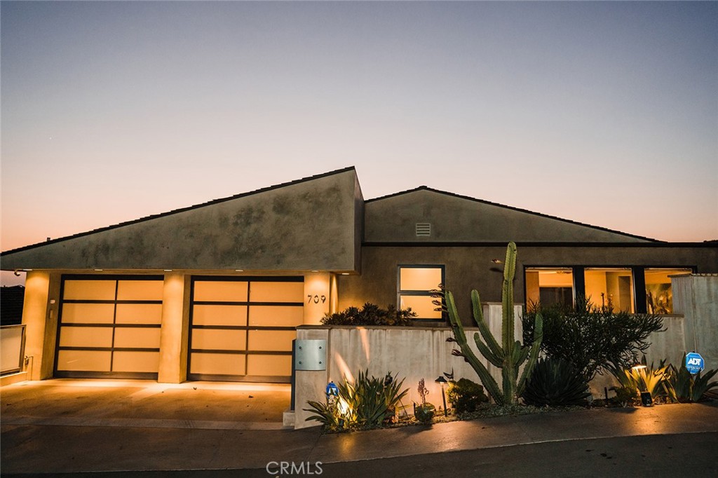 This street-to-street, meticulously maintained, sophisticated, warm contemporary designed property embraces the ultimate indoor-outdoor coastal lifestyle. The unobstructed ocean views of Catalina Island, downtown Laguna Beach Village, Main Beach, Hotel Laguna and spectacular sunset views are a haven of tranquility most can only dream of. The 3,400 sq ft home has 4 bedrooms, 5 1/2 baths and a dual car garage featuring Two Tesla Power Wall-2 units and a multi panel rooftop solar system, as well as entryway to the elevator which serves all 3 levels. Every level, room, and even the garage, are enhanced with exceptional, breathtaking vantage points.
As you and your guests pass through the front walled property with privacy gate, you find yourselves gazing at an impressively unique custom fountain with a koi pond,including potential for a designer rock garden or whatever you may desire.
Abundant natural light from the expansive glass windows and doors invites you into the main living area with its quality hardwood doors and beautiful hardwood floors where the master bedroom, kitchen, and great room with fireplace are located. The romantic master bedroom also has an alluring fireplace, stunning ocean and city light views, a custom walk-in closet, and a spacious granite bathroom with an Oceania tub and separate shower. This classy kitchen hosts sleek European style cabinetry, a grand entertainer’s island, premium integrated Viking appliances, and a walk-in pantry. The spacious upper level bedroom/office and full bathroom top the entryway to the garage. The lower level with light travertine flooring has two en-suite bedrooms and an entertainment room with theater seating.
Peering just outside, you find a tastefully landscaped entertainer’s paradise with a spectacular infinity pool, where you are not sure where the pool and spa end and the great Pacific Ocean begins. Standing under the waterfall will be your favorite covert refuge. You and your guests will appreciate the privacy of the full poolside bathroom with shower and changing area. There is a large custom hammered-copper fire pit, along with two spa-poolside stone fire features to further enhance the mood. Enjoy the preparations from the custom-built outdoor kitchen and toast to your retreat reminiscent of the finest resorts.