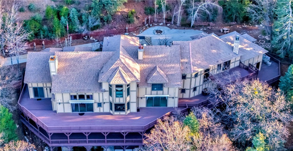 Discover the epitome of luxury at 293 Fairway Drive in the picturesque Lake Arrowhead. This stunning estate offers a seamless blend of modern design and timeless elegance, set against a backdrop of breathtaking mountain views. Encompassing 9,247 square feet, this home features six generously sized bedrooms and seven and a half beautifully designed bathrooms. Guests can enjoy privacy in the upstairs ensuite unit equipped with a fill kitchen and private entrance. The interiors are graced with high ceilings and expansive windows, creating a bright and airy atmosphere throughout. At the heart of the home is the chef’s kitchen, equipped with premium appliances and abundant workspace for culinary adventures. The formal dining room provides an elegant setting for entertaining guests. For relaxation and entertainment, enjoy the well-appointed game room and main floor den, or unwind in the atrium where a soak in the hot tub or steam in the sauna awaits. Wine aficionados will delight in the custom wine cellar, while the expansive deck offers a peaceful retreat with stunning views of the 6.34 acre lot and surrounding forest. Horse stalls, gardens, a pond, and an outdoor kitchen provide the finest in outdoor entertainment. All of this adjacent to national forest trails. Additional amenities such as air conditioning, a washer and dryer, and a spacious garage with parking included ensure convenience and comfort. This remarkable Lake Arrowhead estate invites you to experience a lifestyle of luxury and tranquility in a truly magnificent setting.
