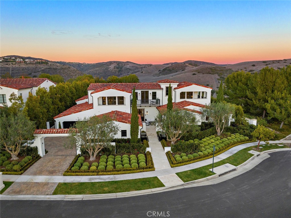 Embraced by rolling hills and peaceful ocean breezes, this top-grade turnkey home in guard-gated Crystal Cove offers lavishly redesigned exterior spaces that create a stunning backdrop for vibrant parties and cozy gatherings alike. Water features flow with tranquility, fire pits cast a warm glow on night skies, and captivating canyon views create a true sanctuary. Newer 2017 construction features incredible recent upgrades that create a luxury experience, w/ a flowing floor plan spanning 8,000 s.f. +/-, and offering 5 bedrooms, 7 bathrooms, and refined finishes that include Venetian plaster walls and ceilings, rift oak doors and cabinetry, and English oak & limestone floors. Seamlessly integrated technology with lightning-fast network speeds offer comfort at the touch of a screen, with eight iPads controlling whole-house Savant automation that accesses everything from surround sound audio to Lutron lighting & blackout shades. Vaulted ceilings with rift oak beams are found in the great room, where a Coronado stone wall brings exquisite texture, motorized pocket doors connect to the outdoor covered patio and a floating glass fireplace links to a dining room with a slab Carrara marble wall. The kitchen is sleek and modern, and offers a rift oak island, quartzite counters, a caterer's kitchen that supports upscale entertaining. A 1,000-bottle climate-controlled wine cellar artfully displays the best vintages, with a glass wall connecting to a study that has evocative marble, and French doors that open to a courtyard with stunning water features. All Bedrooms offer striking ensuites with two main-floor bedrooms including a primary suite with sitting room and an ensuite that offers a book matched marble wall, oversized glass shower, soaking tub, and dual closets. Three upstairs bedrooms include a junior suite with a private terrace, and two guest suites. Also found upstairs are a media room with vaulted ceilings, and a loft. The expansive 19,318 s.f. +/- lot is private with a pool, infinity spa, outdoor kitchen w/pizza oven, BBQ and bathroom, and sound resistant glass fencing. Additional amenities include massage room, whole-house water filtration & softener, 3 HVAC units, security system and gated motor court. Located just a block from the Canyon Club the home offers easy access to recreation and fitness facilities and close proximity to the Crystal Cove Promenade, Crystal Cove State Park & beach, Fashion Island, Laguna Beach, Newport Beach, airport & freeways.