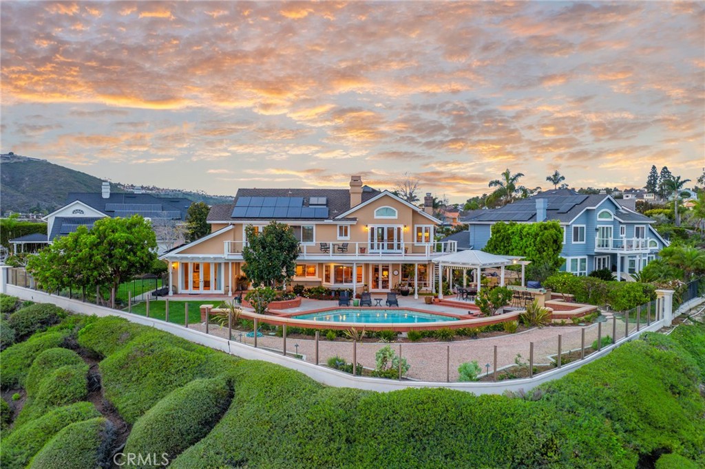 An entertainer's dream awaits in this stunning residence in the guard-gated community of Crest de Ville. Sited on one of the largest lots in the community, measuring approximately 13,986 square feet, 44 New Haven offers unobstructed 180-degree sit-down views, elegant interiors, and unmatched privacy. Meticulously maintained and fully updated throughout, this light-filled home includes four bedrooms, four bathrooms, and two additional multipurpose spaces. The ground level features a dedicated entry, a double-height formal sitting room with a fireplace, and an adjacent dining area with a temperature-controlled wine cellar. The kitchen, which opens to the living section, abounds in highlights such as updated appliances, granite countertops, a travertine backsplash, and a breakfast nook. Accessed through French doors, the breathtaking backyard boasts a custom pool and spa, an outdoor kitchen, and a covered sitting area – ideal for year-round enjoyment. A coveted main-level private ensuite bedroom and a home office that could serve as sleeping quarters complete this floor. A fireplace anchors the upstairs primary suite with a large balcony for taking in spectacular ocean views, a spa-like bathroom with travertine flooring, a walk-in closet, and a connected multipurpose room. Secondary bedrooms on this level share an updated full bathroom with dual sinks. A spacious, airy bonus room with abundant built-in cabinetry rounds out the upper level. Extensive upgrades include solar panels, a security system, a central vacuum, updated air conditioning, and plumbing. In addition to around-the-clock security, Crest de Ville amenities comprise a pool, spa, playground, and sports court. The central location allows for access to renowned resorts, world-famous beaches, and convenient shopping in mere minutes.
