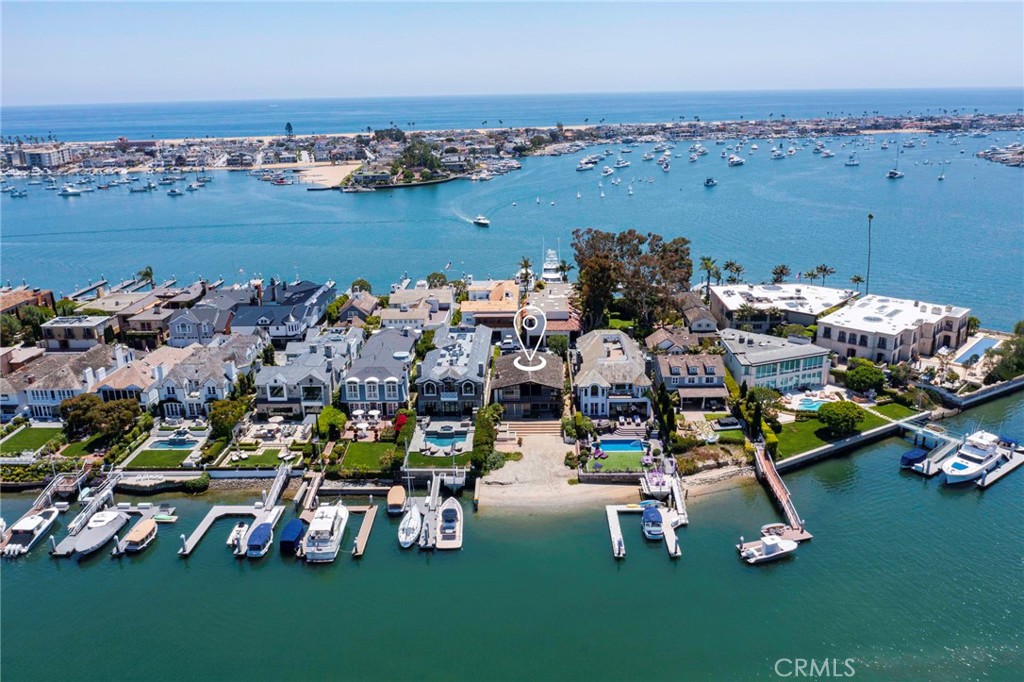 This amazing, one-of-a-kind bay front parcel and iconic mid-century modern home has been in the same family since the lot was first purchased in the 1930’s. The current family grew up in this home which was constructed and designed in 1961 by their father. Years of love, enjoyment and quality family time has created an extraordinary opportunity for the next lucky owner to be a part of this memorable legacy. The massive 8450 square foot lot offers 50 feet of water frontage, unobstructed waterfront views and sandy beach on the most sought after island anywhere in Southern California. The timeless and authentic mid century architecture was considerably ahead of its time and features an open Great Room with floor to ceiling windows that creates abundant natural light, a floating steel staircase, iconic fireplace surround with built-ins, open Chef’s kitchen, main floor guest room with en-suite bath, family room and full bath with direct access from the beach. Upstairs you’ll find a flexible configuration of up to 5 bedrooms plus 2 full bathrooms with floating sinks and authentic tile from the mid century era. The open floor plan continues upstairs without closed-in hallways and features massive vaulted ceilings with tongue and groove hardwood accents and towering windows that created an ambience like no other. The master suite offers a spacious master bath, walk-in closet, vanity and private balcony to take in the spectacular and mesmerizing views. Offering an over sized 3 car garage with rare parking for 4 to 5 additional cars in the massive driveway. Enter exclusive Harbor Island over a private bridge and past the guarded gate onto an enchanting cobblestone street that hosts some of the most prestigious families and waterfront estates found anywhere in the US. Close to everything Newport Beach has to offer yet feels so far away from the “hustle and bustle” of everyday city life. Clearly a home for the most discerning Buyers looking to create their own legacy and memories.