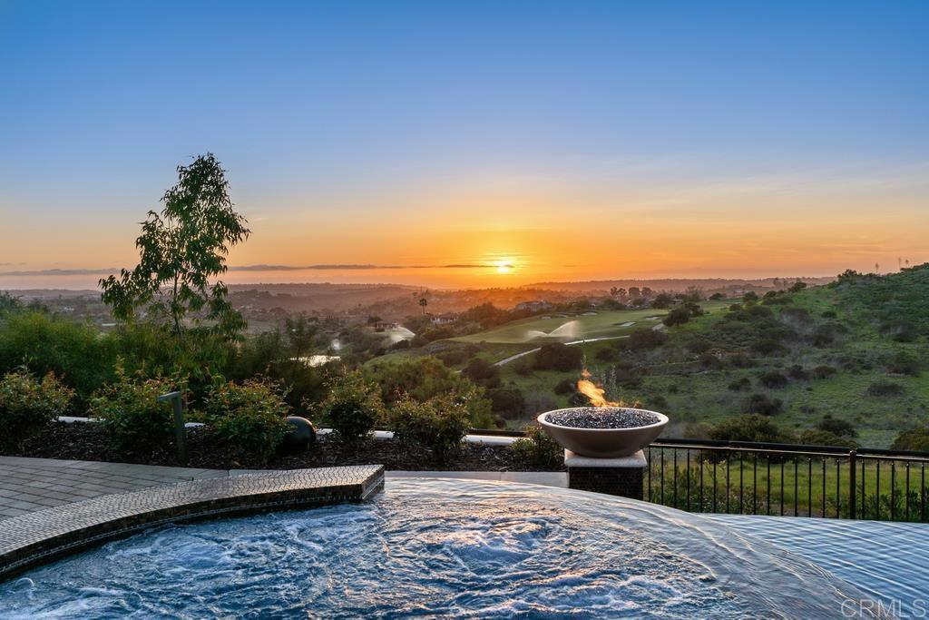 Welcome to an exceptional modern retreat situated in the exclusive guard-gated Santaluz golf community. This bespoke contemporary residence is ideally situated at the pinnacle of a tranquil cul-de-sac, providing breathtaking 180-degree vistas of the Ocean, Lake, and the expansive Golf Course landscape. Step inside to discover a meticulously crafted residence, where every detail is thoughtfully curated to evoke luxury and sophistication. From the solid Mahogany doors to the awe-inspiring chandelier, the home boasts an array of exquisite designer touches. The seamless open-concept floorplan with volume ceilings creates an inviting atmosphere, ideal for entertaining guests in the expansive Great Room and Gourmet Kitchen, complete with Onyx stone countertops, Wolf appliances, and a custom wet bar. Enhancing the indoor-outdoor living experience are motorized glass panels that effortlessly transition to a covered loggia adorned with a fireplace, offering captivating panoramic views of the surrounding landscape. Step outside to discover resort-style amenities, including a saltwater heated infinity pool and Jacuzzi, an inviting outdoor fire pit, and a pool casita equipped with a kitchen and BBQ. Retreat to the Master Suite, a sanctuary boasting a private viewing deck and an oversized bathroom suite adorned with luxurious mother-of-pearl accents. Additional property amenities include a sauna, elevator, temperature-controlled wine room, a dedicated dog and cat room with heated floors, and a home theater, where a color-changing sky ceiling sets the stage for unforgettable entertainment.