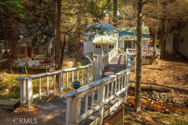 Romantic Cottage close to town! Enter on the private bridge that takes you across the babbling stream to this tranquil three bedroom, two bath retreat in the woods. This home boasts hardwood floors throughout, an updated kitchen and bathrooms, new window blinds, and vaulted beamed ceilings. Other features include level entry, separate dining room and eating area in the kitchen, two decks, and two storage areas. Walk to Blue Jay for shopping and entertainment!