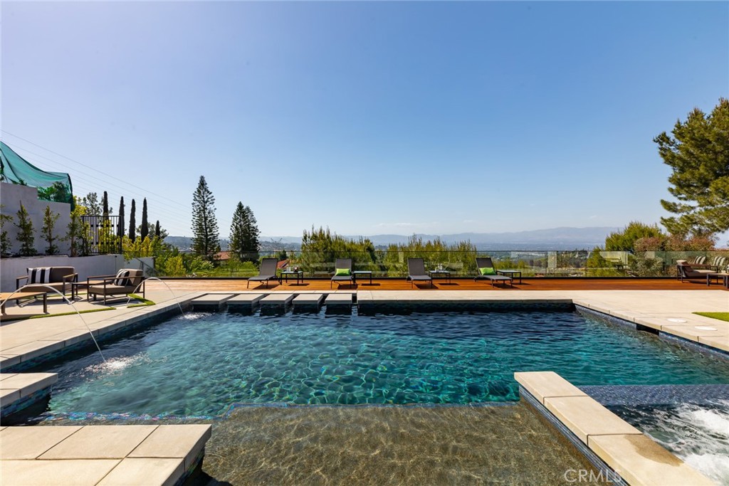 Views views views!!! Masterfully designed, privately gated with the ultimate luxury located in prime South of the Boulevard Encino! Imbued with modern elements that was fully and completely remodeled, this unique home features five bedrooms, five bathrooms and 2 laundry rooms.
Earthy walnut cabinetry and cool toned stone throughout, creating a stylish balance of formal spaces and cozy living. The front pivoting walnut door enchants as it compels you through this stunning home equipped with high ceilings, custom built-ins, premium finishes, and ample natural light with Elan smart home, in-ceiling speakers throughout. This exquisite residence features a captivating two level design.
The open floor plan with an abundance of natural light is adjourned with the finest amenities including a media room, office, spa, sauna, pool and more.
This house has it all!
Past the gates The wide entry hallway with ultra high ceilings and European walnut floors welcomes you to the dazzling living room with stone entertainment bars and a formal dining room with a bar and wine cellar. Through the entry hall past the designer lighting guide you to the sophisticated family room with high and original unique ceilings with exposed beams. Across is the awe inspiring kitchen with a beautiful island, Sub zero and Wolf stainless steel appliances with panel ready refrigerator. Breakfast nook and all conveniences for the gourmet chef. Custom designed state of the art media room and private office with gorgeous builtins complete the first floor. Take the lighting staircase up past the designer chandeliers to the opulent primary bedroom with gorgeous wood floor and fire place, custom built-ins. This unique design has an oversized master bathroom with sauna and steam shower and 2 walk-in closets. Hidden room behind the laundry room to keep valuables. Master has break taking views from windows and balcony. 3 other en-suites with spacious closets and laundry room complete the 2nd floor. The backyard is exquisite with a covered patio and deck with concrete patio around the entire pool and Ipe wood deck with glass railing, Large pool and oversized spa and outdoor kitchen with bar counter and cabana with plenty of space to host and enjoy a nice outdoor dinner or BBQ night. Outdoor music sounds system for extra entertainment.
House has 3 car garage with plenty of space to park multiple vehicles. Don't miss this unique house! One of a kind unicorn.