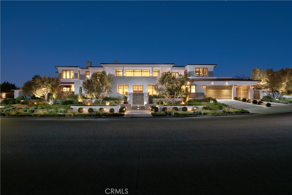A showpiece of design, this Eastern seaboard-style estate of peerless craftsmanship and mesmerizing ocean views exemplifies effortless coastal living. The stylish residence was reimagined by well-regarded architect Bob White and Spinnaker Development with interiors by Kelly Nutt Design and landscaping by Garden Studio Design. Set within the picturesque community of Harbor View Hills, the one-of-a-kind 15,400 SF (appx.) parcel is perfectly positioned to capture endless blue water vistas from nearly every vantage point. Lighted steps of a gated entry lead to a custom pivot door which introduces the sprawling interiors fit with a myriad of luxury amenities, extraordinary finishes, and bespoke details throughout. Anchored by European white-oak planks by Gaetano Hardwood Floors, beamed ceilings, wainscoting, skylights, and a wood-burning fireplace, the grandly proportioned living spaces display a masterful expression of architecture while imbuing warm natural light throughout the home. The designer kitchen caters to chefs and entertainers alike with two expansive dual quartz-topped islands (one counter height and one bar height), petite granite on perimeter counters, zinc-finished pendants, Waterworks faucets, full-service butler's pantry, built-in Miele, Sub-Zero and Wolf appliances, and glass windows that fully open to reveal the resort-style backyard. Occupying a separate wing of the main-level, the fireplace-warmed owner's suite is a sumptuous retreat characterized by paneled ceilings, two walk-in closets, limestone flooring in the spa-like bath, dual vanity sinks, walk-in shower with dual shower heads, and a Victoria + Albert tub. Rounding out the main level is an open-plan dining room, secondary living room, two baths, and a generously sized office with built-in workspace and balcony. Descending one level, a fully equipped kitchenette services a media room/lounge area curating an idyllic space for large gatherings. Three bedrooms (two of which are en suite), study area, large laundry room, mudroom, and full bath, complete the level. Embrace year-round entertaining and easy outdoor dining with bar seating before a barbecue, built-in firepit, pool, and cascading spa. Further highlights include an elevator, nest thermostats, Control4 home automation, Lutron lighting system, and security cameras. Set just moments from Fashion Island, championship golf courses, and famous beaches, 1100 Ebbtide's location and lifestyle are without rival.