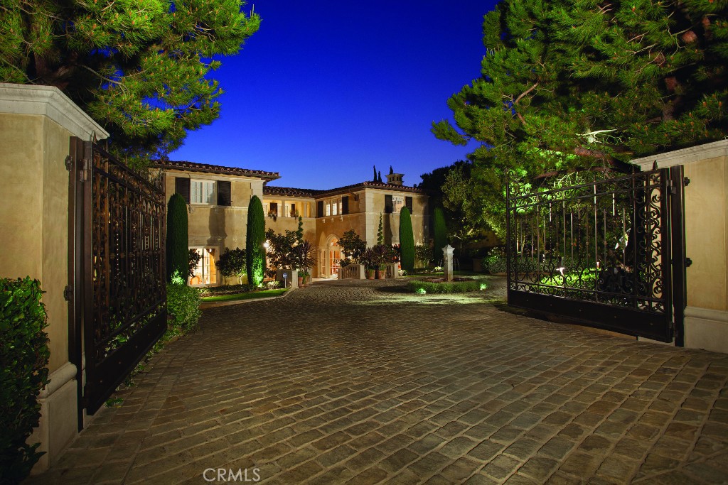 DON'T BUY ANOTHER HOUSE UNTIL YOU HAVE SEEN THIS ONE! Nestled behind iron gates on an unmatched oversized lot, the timeless Old World elegance of this estate is evident from the moment you walk in. The main floor features a handsome wood paneled library with wet bar, huge great room with distressed walnut floors, imported antique fireplace, and impressive ocean views that are shared with the adjoining formal living room. There is also an elevator that services all three floors of this grand estate. The entertainment level lends endless opportunities for you and your guests featuring a voluminous theater complete with a 12'screen, an immense game room, bar with adjacent outdoor courtyard, and a fully mirrored gym. The upper level is home to 3 large bedroom suites complete with walk in closets, full baths, the glorious Master Suite with his and hers bathrooms and closets, heated floors, and over 1000 sq ft of decks with commanding views of Newport Harbor, Catalina, mountain and city lights all the way to Palos Verde and beyond. No showings until after August 1st