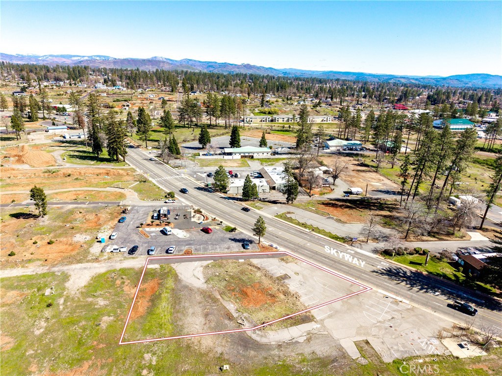Exceptional opportunity to own a 0.55-acre commercial lot in the heart of Paradise. This property, which boasts 98 feet of Skyway frontage, is ideally located in the center of town, providing high visibility and accessibility. A structure of over 22,000 sq ft is permissible on this property. Previously the site of the successful business Juice and Java, its location guarantees consistent traffic and optimal exposure for any enterprise. The property is relatively flat, featuring two convenient access points—one directly from Skyway and another from an owned, private access road bordering the lot—making entry and exit seamless. This attractive property includes an engineered septic system (in good condition), an active PID water account, and a partially developed parking area that lays the groundwork for future expansion. Commercially zoned lots in such a prime, central location are rare! Whether you aim to launch a new business, relocate, or invest in a high-demand area, this versatile property presents incredible potential.