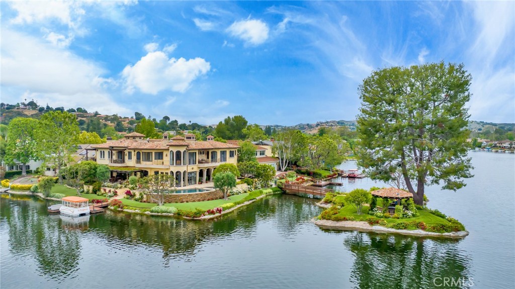 Re-discover luxury with this lakefront home that boasts a unique blend of Italian Style, modern luxuries & is connected to the iconic "Hope Island". The 100-year-old reclaimed roof tiles imported from Italy coupled with beveled glass lends character to the house which is situated on one of the best locations on the lake. Stepping into the home you are greeted with an abundance of natural light that floods every corner. This home offers comfortable public spaces that seamlessly integrate with the amazing outdoor entertaining areas creating the ultimate California indoor/outdoor lifestyle home. The chefs kitchen features top of the line appliances coupled with an oversized Brazilian quarts island sets the perfect tone for entertaining guests. Take the elevator with designer mosaic-tile floors to the first primary suite & experience craftsmanship like no other. There are two primary suites with connecting balconies. The spa like master bath is complete with a morning bar for convenient coffee or chilled drinks. The second primary suite has a centerpiece limestone fireplace with hearth & mantle. Just steps away you can enter the work out room fitted with a sauna. Step outside to the wrap around patio providing unobscured views of the main channel & enjoy the firepit, vanishing edge pool or spa. The custom dock is conveniently housing your electric boat for sunset cruises or dinner on the water at the Landing or the famous Boccacios. Lastly, the Oregon cedar bridge leading to the island on the lake with matching 100-year-old reclaimed roof is the perfect retreat to enjoy the breathtaking sunsets. This home was built to perfection & has too many details to list.