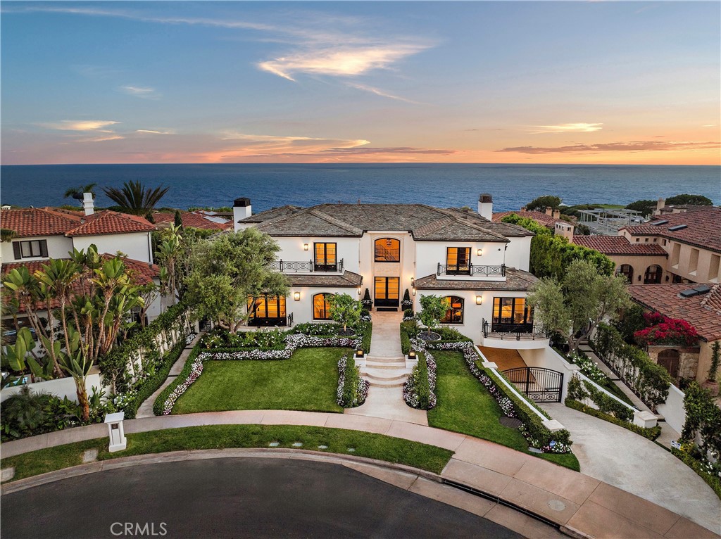 CREATIVE FINANCING AVAILABLE. INQUIRE FOR DETAILS. Indulge in the pinnacle of luxury living with this extraordinary estate in the exclusive gated Pelican Point community where the sound of white-water waves crashing on the shore and the sighting of whales and dolphins are just part of a normal day. Offering unmatched privacy and the most expansive view frontage in the area, this property is a sanctuary of refinement. Masterfully rebuilt in 2009 and meticulously updated in 2024, this custom residence epitomizes neoclassical grandeur with an eye for modern elegance. Boasting five spacious bedrooms and eight bathrooms in 7,300 +/- square feet on a 13,000 +/- square foot lot, the home effortlessly blends formal and informal living spaces. Every inch has been crafted with unparalleled attention to detail, featuring rare, hand-selected stones and hardwoods, artisan-crafted surfaces, and solid wood finish carpentry. The property is adorned with designer lighting and fixtures, top-line appliances, dual staircases (formal and service), and a convenient elevator reaching all three levels. The interior space is a masterclass in updated elegance, offering a seamless flow between rooms that enhances both sophistication and comfort. Every window frames a picturesque vista, ensuring that the ocean’s splendor and the captivating sunsets are always within view. Enjoy cinematic experiences in the state-of-the-art cinema room or entertain in style with a sophisticated wine cellar that holds over one thousand bottles, all within an ambiance of contemporary sophistication. Step outside to find an exterior as breathtaking as the interior with an uncommonly distinctive front curb appeal and lush, manicured grounds that envelop the estate, highlighted by a 128-foot terrace of exquisite French limestone. Dive into the sparkling knife-edge swimming pool, clad in luxurious Italian granite slabs, while savoring the panoramic views of Newport Coast that stretch as far as the eye can see. Additional features include a finished garage with space for three cars and a separate gated drive accommodating five more vehicles. With guard-gated security, private direct beach access, and proximity to the region’s most coveted amenities, Pelican Point provides an unparalleled lifestyle as the only gated community in Newport Coast where you can hear the ocean waves. This estate is more than a home; it’s a gateway to a life of luxury, combining timeless elegance with spectacular natural beauty.