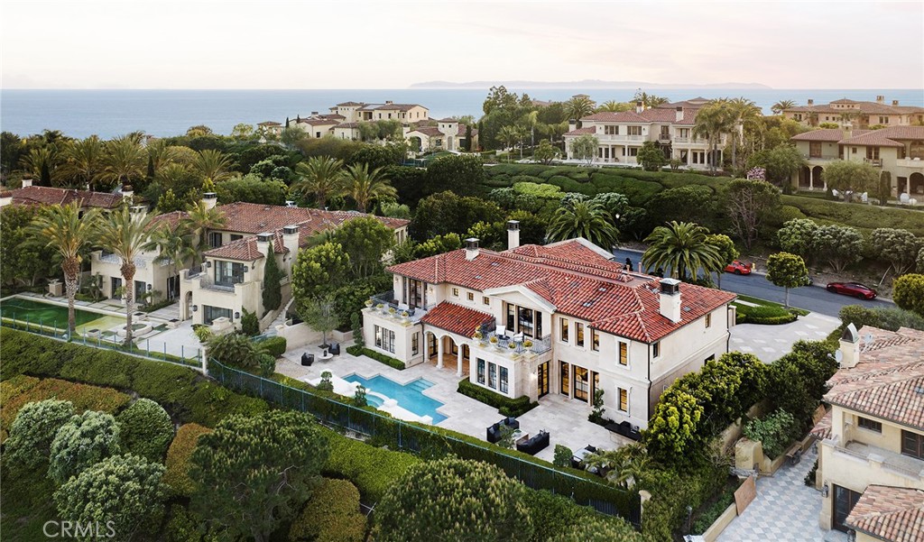 Located within the exclusive custom home community of Pelican Crest, this remarkable, recently-refreshed residence offers timeless style, with a flowing 6,727 s.f. +/- floor plan that’s enhanced with exceptionally tall ceilings and exceptional materials. An impressive entry hall with a statement staircase and flowing natural light is a central hub that seamlessly connects to spaces designed to welcome guests in lavish style; a dining room with a stone-trimmed fireplace and exquisite French windows, an office with custom built-ins and a generous sitting area, a spacious lounge with backlit cove ceilings (or second office) and a living room with a stone fireplace facade that soars to double-height ceilings. The family room draws friends and family together into a social space that evokes inviting warmth, with a wet bar and coffered ceilings, and an open layout that links with the gourmet chef’s kitchen, breakfast room, and outdoor spaces. Four bedrooms and 5 bathrooms offer bespoke luxury; two downstairs bedrooms look out on meticulous gardens, and offer ensuite baths with stone surfaces, and two upstairs bedrooms include a junior suite with a breezy balcony, and a massive primary bedroom with a double-sided fireplace, sitting area, ocean-facing balcony, and a palatial ensuite bath and walk-in closet. The lot offers a generous 15,547 s.f. +/- of outdoor spaces as well as a finished 3-car garage, with carefully placed trees and greenery creating a backyard that’s buffered and private. A spa flows into the pool with a cascading water feature, a covered loggia connects to the living room, and an expansive stone patio creates areas to lounge in the sun or entertain in the BBQ kitchen with bar seating. Living well never goes out of style in the guard-gated Pelican Crest community, where residents enjoy world-class amenities: Fashion Island shopping and dining experiences, nearby golf at Pelican Hill Resort, Crystal Cove’s pristine beaches, and easy access to freeways and John Wayne Airport.