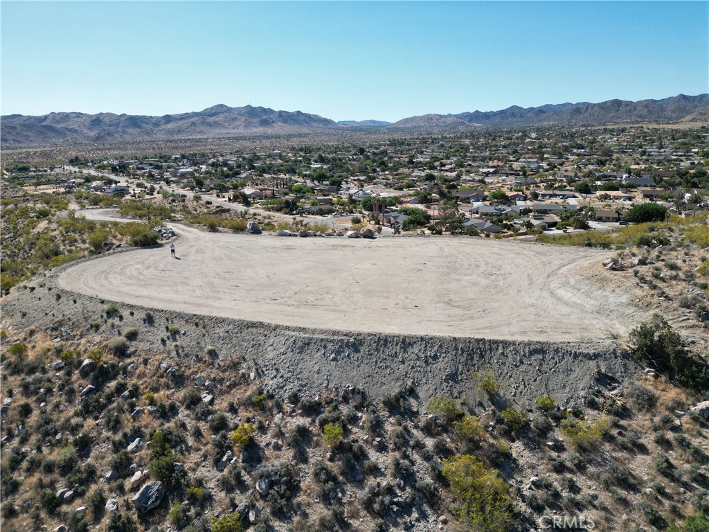Experience a once-in-a-lifetime opportunity to own 20 secluded acres off Scenic Mountain in the coveted Sky Harbor area of Yucca Valley. Unlike other properties that merely claim panoramic views, this one truly delivers. The expansive 20,000 square foot building pad is complemented by a gated, block walled entry and a smooth, 900-foot graded driveway, complete with drainage areas along the sides. Enjoy breathtaking views in every direction, framed by stunning desert plants and unique rock formations. This parcel is zoned Residential, Single Family (RR-0.5), offering a prime opportunity to build your dream home or investment property. With its residential zoning, the property allows for a wide array of custom single-family home designs on generous half-acre lots, perfect for those seeking space, privacy, and a connection to the beautiful natural surroundings. The owner reports that a water meter is already in place and other utilities are conveniently close to the property’s entrance (buyer to verify). The seller has already completed an aerial survey, providing precise measurements and an accurate representation of the land's topography. This valuable resource will save you time and effort as you begin planning your build. With the possibility of owner financing available under acceptable terms, this unique property is a rare find. Visit today and see for yourself why this is a special opportunity unlike any other in the area. Check out the video of the property here https://youtu.be/jSqMqxid0ps