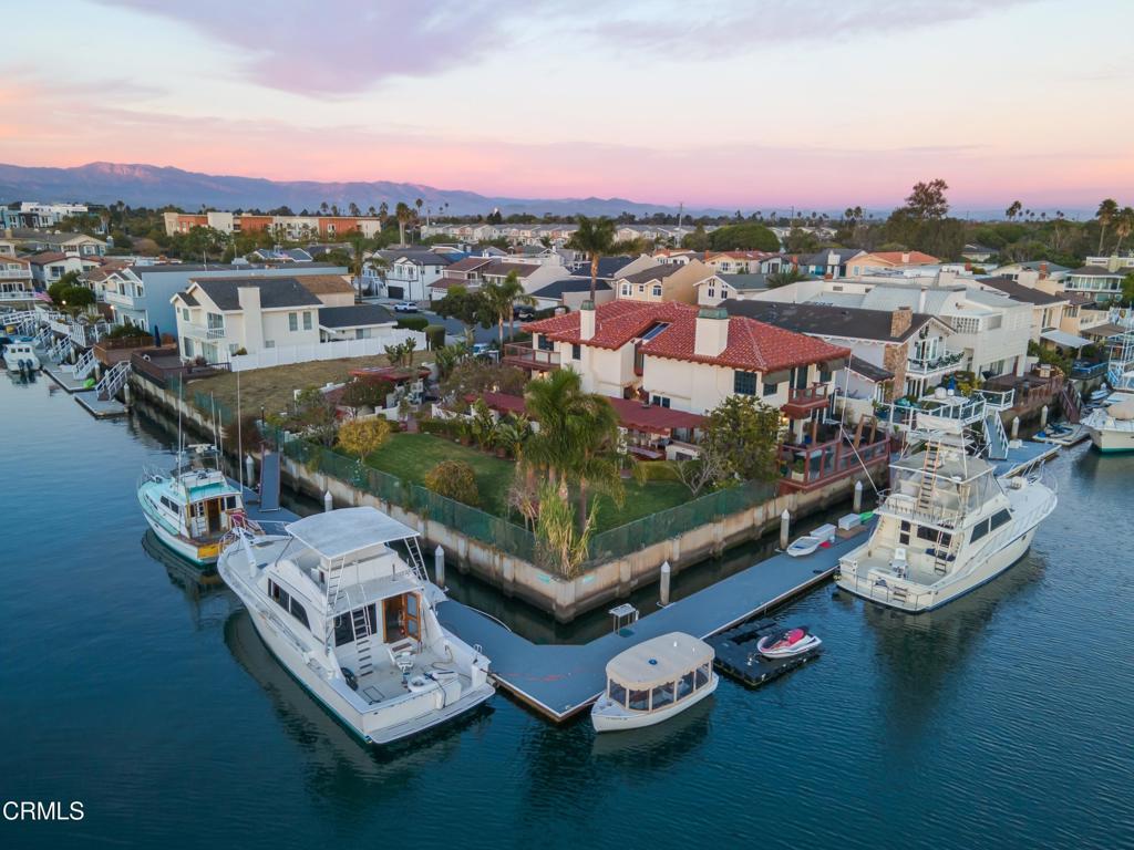 This truly one-of-a-kind residence in the heart of Channel Islands Harbor is curated for those who appreciate the finer things in life. Here you'll find a rare corner point home, a testament to luxury living and the iconic Southern California coastal lifestyle. Featuring 3 bedrooms, 3 bathrooms, and a sprawling 4,138 square feet of meticulously designed interior space, it's set on an expansive double lot of more than 12,000 square feet including the corner lot, ensuring privacy and limitless potential. An avid boater's dream, this home features massive boat slips measuring an impressive 130' and 135'. Outdoor spaces include a summer kitchen, outdoor shower, terraces, and greenspace, all with stunning waterfront views, offering an idyllic setting for outdoor living, gathering, and entertaining. Interior design details include Spanish tile flooring, stone fireplaces, skylights, custom cabinetry, exposed-beam ceilings, and sophisticated fixtures and finishes. Open-concept main floor living space includes a showstopping bar, walls of windows, custom millwork, and an expansive kitchen with a butcher block-topped center island, serving bar, and adjoining dining space. Fabulous owner's retreat features a walk-in closet, huge en suite bath, wet bar with beverage fridge, and a spacious sauna. Nestled midway between bustling LAX and the serene beauty of Santa Barbara, the setting offers coastal weather that complements the minutes-away access to the beach. Seamlessly transition from land to sea, boating to nearby restaurants, yacht clubs, or the enchanting Channel Islands.