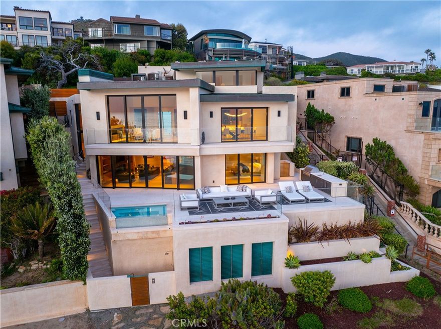 This is more than just a home; it’s a lifestyle. Your dream coastal retreat is a stunning contemporary estate nestled on pristine sands in Lagunita, one of a few gated beachfront communities in Laguna Beach. This magical setting features 270-degree panoramic ocean views encompassing Catalina Island in front, the Montage on the left, and Victoria Beach on the right. Whales nuzzle against the boulders in the center of your view, an incredible glimpse of the natural world at your doorstep. Designed by esteemed architect Stephen Thompson and renowned builder Tony Valentine, this residence represents the pinnacle of craftsmanship and style, where every detail reflects a commitment to quality and excellence. 



Ground up remodel in 2018, the home offers 6,738 sq ft of luxurious living space across four levels, meticulously crafted for both grand entertaining and intimate gatherings. The 54 feet of beachfront allow you to relish the serenity; outdoor living space offers direct community steps, beach access, on-deck infinity spa, Lynx grill, and al fresco kitchen. Expansive interior features four en-suite bedrooms, office, and a total of eight beautifully appointed bathrooms. Design details include four custom fireplaces swathed in onyx & marble, plus a one-of-a-kind stone mantel embedded with fossils. Nearly 12-foot-high ceiling in living room, unique among beachfront homes, add to the sense of space and drama. 



Dedicated entertaining space features a custom semicircular movie theater with unparalleled acoustics, billiard room with seated bar, 420-bottle wine cellar, video game room & bathroom, gym, locker room and steam/sauna. Gourmet kitchen is equipped with top-of-the-line Miele and Viking appliances with a bulthaup hood fan. Elevator serves all four levels and three-bay garage, a rarity in this exclusive area. This is truly the ultimate in Laguna Beach luxury — and it’s waiting for you.