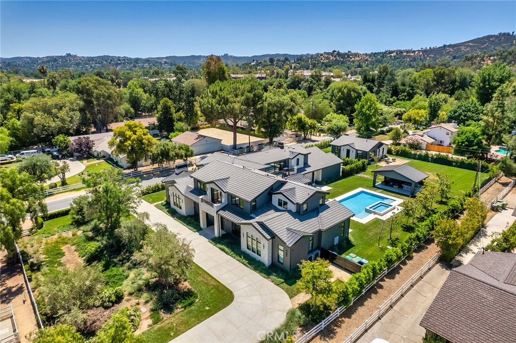 This beautiful new contemporary farmhouse is sited among mature oak & olive trees and nestled on a large, over one-acre flat lot. Step through the custom iron & glass door into a world of elegance & luxury. The spacious open floor plan features huge picture windows and sliding walls of glass that flood the home with natural light. Highlights include a gorgeous chef's kitchen with large adjoining butlers pantry, formal dining room with refrigerated wine storage, wonderful entertainers game room with large serving bar, family room with stone fireplace, gorgeous home theater with upholstered walls, plus a custom office and an architectural floating staircase. There are five bedrooms in the main house, and two more in the large guest house. The superb primary suite offers a bookmatched stone shower wall, soaking tub, room sized custom closet with aluminum & glass cabinets, and a walk-out balcony with views overlooking the lushly landscaped grounds. The nicely private grounds include a guest house with kitchen & family room, a pool cabana complete with full barbecue center, a sparkling, resort style pool & spa, and expansive lawns with room to roam. The home also offers easy access to the community hiking trials and the nearby community recreation center with sports courts, community activities, and a Tuesday afternoon farmer's market.
