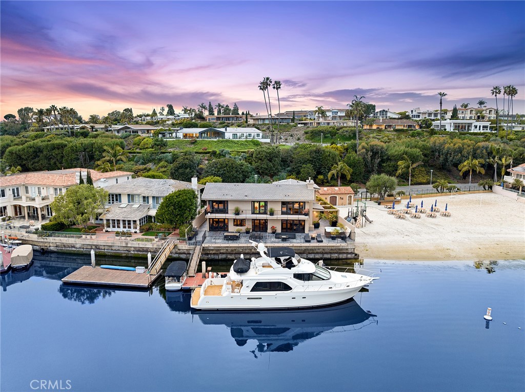 1.2M PRICE REDUCTION ---- 1106 Polaris Drive presents a rare opportunity to own a waterfront home sited on an approximately 6,900 square foot oversized lot in Dover Shores proper, one of the largest in the neighborhood. Spanning roughly 3,320 square feet, this property features a rare 76’ of bay frontage and a large dock ready to accommodate a vessel as large as 85’. Beyond the secure entryway and accented by multiple skylights, the front atrium houses the indoor pool. The main area of 1106 Polaris Drive features a living room anchored by a large fireplace, an adjacent dining area complete with a wet bar, and a kitchen with a sitting area. Multiple French doors lead to the spacious outside patio ideal for outdoor entertaining. Two bedrooms, two bathrooms, and a utility area complete the main level. Upstairs the spacious primary retreat of this home features a vaulted ceiling, a slab-mantle fireplace, and a sitting area. The windows of this space perfectly frame the view of bay with Fashion Island in the distance and the French doors provide access to the balcony which spans the length of the property. The ensuite bathroom is comprised of a double vanity, an oversize soaking tub, and a large walk-in shower. A secondary master suite and an additional bedroom complete the upper level. The coveted Dover Shores homeowners’ association amenities include access to three private, resident-only beaches. 1106 Polaris features an unparalleled location within the Mariners school district, just minutes away from conveniences of 17th Street, famous local beaches, John Wayne Airport, and Fashion Island.
