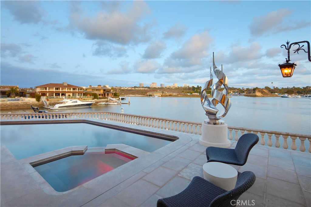 Showcasing approximately 148 feet of prime bay frontage from its exceptional end-of-cul-de-sac location in Newport Beach’s prestigious Dover Shores, this extravagant custom estate elevates waterfront living. A private dock that can accommodate multiple vessels is one of the countless luxurious that are revealed at the European-style villa, which is set behind gates and hosts five en suite bedrooms and six-and-one-half baths. Approximately 6,601 square feet, the opulent residence impresses upon arrival with an open-concept main level that frames views through extensive walls of telescoping glass doors, bringing bay, marina and city-light views into living areas of genuine distinction. The living, dining, and family rooms open directly to a massive waterfront terrace with a resort-caliber pool and spa, open-air fireplace, and an outdoor kitchen with grill and bar. Bay views continue in the kitchen, which hosts an island with waterfall edges, a pass-thru to the terrace, solid stone sink, walk-in pantry, Miele coffee station, wine fridge, and a gorgeous Lacanche range with pot filler. Three bedrooms and an office are located on this level, which also features a two-vehicle garage with two lifts accommodating up to four vehicles. An elegant circular staircase leads to the second level, where a rotunda opens to a romantic Juliet balcony overlooking the entry courtyard. A plush theater with enormous screen and wet bar, a fireplace-warmed office, and an exercise room join a secondary suite upstairs. The primary suite reveals an entrance with two hand-carved doors and a cross-loin ceiling, and a vaulted ceiling soars over the bedroom. Enjoy a fireplace, deck with panoramic bay and city views, two boutique-inspired walk-in closets, a solid stone freestanding tub, oversized multi-head steam shower, sit-down vanity and two sinks overlooking the bay. Additional highlights include lighting and alarm systems, custom shades, and built-in audio. Your desirable address in Dover Shores places you merely moments from community parks, Back Bay trails and the Newport Aquatic Center. Westcliff Plaza, Fashion Island, and miles of beaches are minutes from home, and a variety of award-winning public and private schools serve all grade levels. Rarely available, this extraordinary estate offers the unparalleled waterfront lifestyle you’ve been seeking.