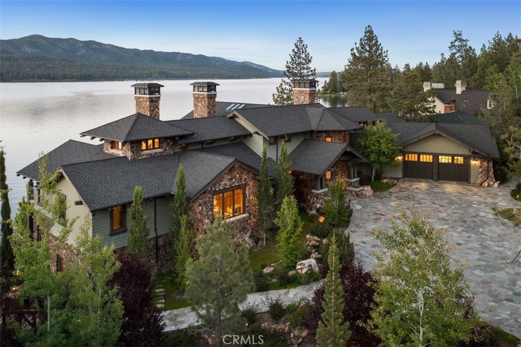 It took a collaboration of master craftsmen, designers, and curators, and almost a decade of construction with unsurpassed attention to detail and focused intention in every feature and appointment to create this inspiring Big Bear Lakefront masterpiece affectionately known as TWIN PINES. The pinnacle of lakefront living in Big Bear, and perhaps in all of Southern California, Twin Pines blends the finest elements of Craftsman, European, Rustic/Southwest, and Distinctive Contemporary design to invoke a uniquely comfortable yet elegant ambiance. From soaring cathedral ceilings with hand hewn antiqued beams, artist inspired backlit stained glass showpieces, amazing panoramic views from almost every room and balcony, the most intricate details in every aspect of finish work, to the intentional selection of every individual piece of art and décor, this home is simply unsurpassed.
In a highly sought-after deep water, wind protected cove on the lake, you'll enter Twin Pines through a gated entrance leading to a parklike setting where stone paths wander past lush landscaping of Weeping Sequoias and native boulders to the water's edge with over 200 feet of lake frontage. Lakeside terraces include two sprawling lawns, a campfire retreat, a custom 2-story playhouse, a flagstone patio with pergola at lake's edge, artisan inspired mosaic seating area, outdoor shower, and a terrace level kitchen and bath.
Functionality was not ignored at Twin Pines with a full Lutron system offering the best in smart home technology for lights, climate, music, shades, security and more. Radiant heat and air conditioning throughout offers cozy, consistent temperatures year round and even services the garage and driveway areas. There's elevator access to all levels, and of course, a security gate with remote accessed intercom and full custom iron fencing to respect your privacy.
With Twin Pines only a few hours drive and less than an hour's flight from almost anywhere in Southern California, you won't find a quicker, easier or more convenient access to world class alpine lakefront living anywhere else. Relaxing lakeside, spending a day on the slopes, going on a hike or bike ride in the mountains, or boating on our mile-high blue jewel called Big Bear Lake from your luxury Big Bear retreat will always be just moments away.
With far too many features to list, you are welcomed to a private showing to share with you the entirety of what Twin Pines has to offer!