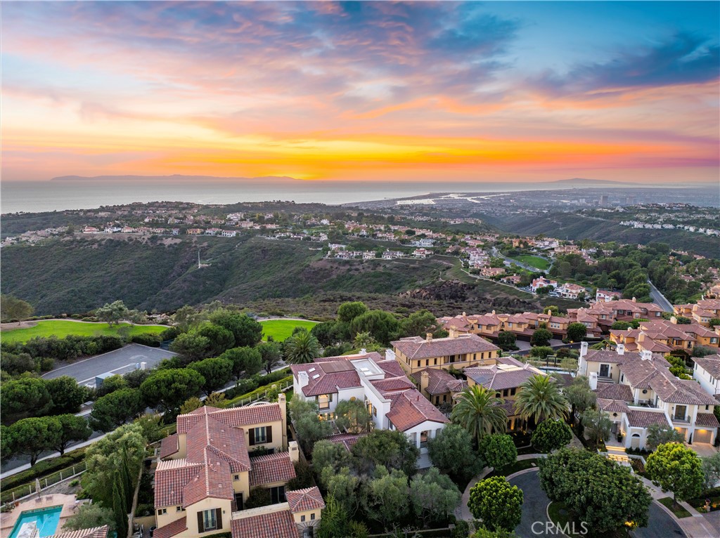 Nestled on a tranquil cul-de-sac in Newport Coast's prestigious Ocean Heights community, this hilltop estate offers 6,000 square feet of luxurious living space. Meticulously renovated and completed in 2024, the property boasts breathtaking panoramic views of the ocean, city lights, harbor, Catalina Island, and Palos Verdes, creating a dreamlike backdrop from nearly every room. Upon arrival, an elegant courtyard with mature olive trees and a sophisticated outdoor fireplace sets the stage for the grandeur within. Enter through 10-foot double-glass doors into a grand foyer with soaring 20-foot ceilings and exquisite custom flooring. The open-concept floor plan allows for seamless transitions between the living, dining, and family rooms, with La Cantina folding doors opening to a beautifully landscaped backyard and stunning ocean vistas, perfectly embodying indoor-outdoor living. The home features up to six opulent bedrooms, including a main-floor guest suite and four en-suite bedrooms on the second level, plus an office or bedroom. High ceilings and custom flooring enhance the sense of coastal elegance throughout. Large picture windows flood every room with natural light, highlighting the dramatic views and creating a bright, airy ambiance. The gourmet kitchen is a chef’s dream, boasting a 12-foot island, custom milled wood cabinetry, and Thermador appliances. Ocean views and seamless connections to the family room make it ideal for entertaining. Upstairs, discover two newly constructed office/bedrooms with vaulted ceilings and large picture windows for expansive ocean views. The oversized primary suite features designer finishes, custom built-ins, and panoramic views. The spa-inspired bathroom offers a standalone tub and expansive shower, providing a sanctuary of elegance. The outdoor spaces rival those of a world-class resort, featuring a shaded loggia, manicured lawn, vibrant gardens, and multiple sitting areas. This property is perfect for enjoying Pacific sunsets or hosting elegant gatherings, with every detail crafted for seamless indoor and outdoor living. Residents enjoy access to the Coastal Canyon Clubhouse and are minutes from Crystal Cove State Park, upscale shopping, and dining. Located near UC Irvine and John Wayne Airport, this estate is about 45 minutes from Los Angeles and San Diego International Airports, offering the pinnacle of chic coastal living and urban convenience in Newport Coast.